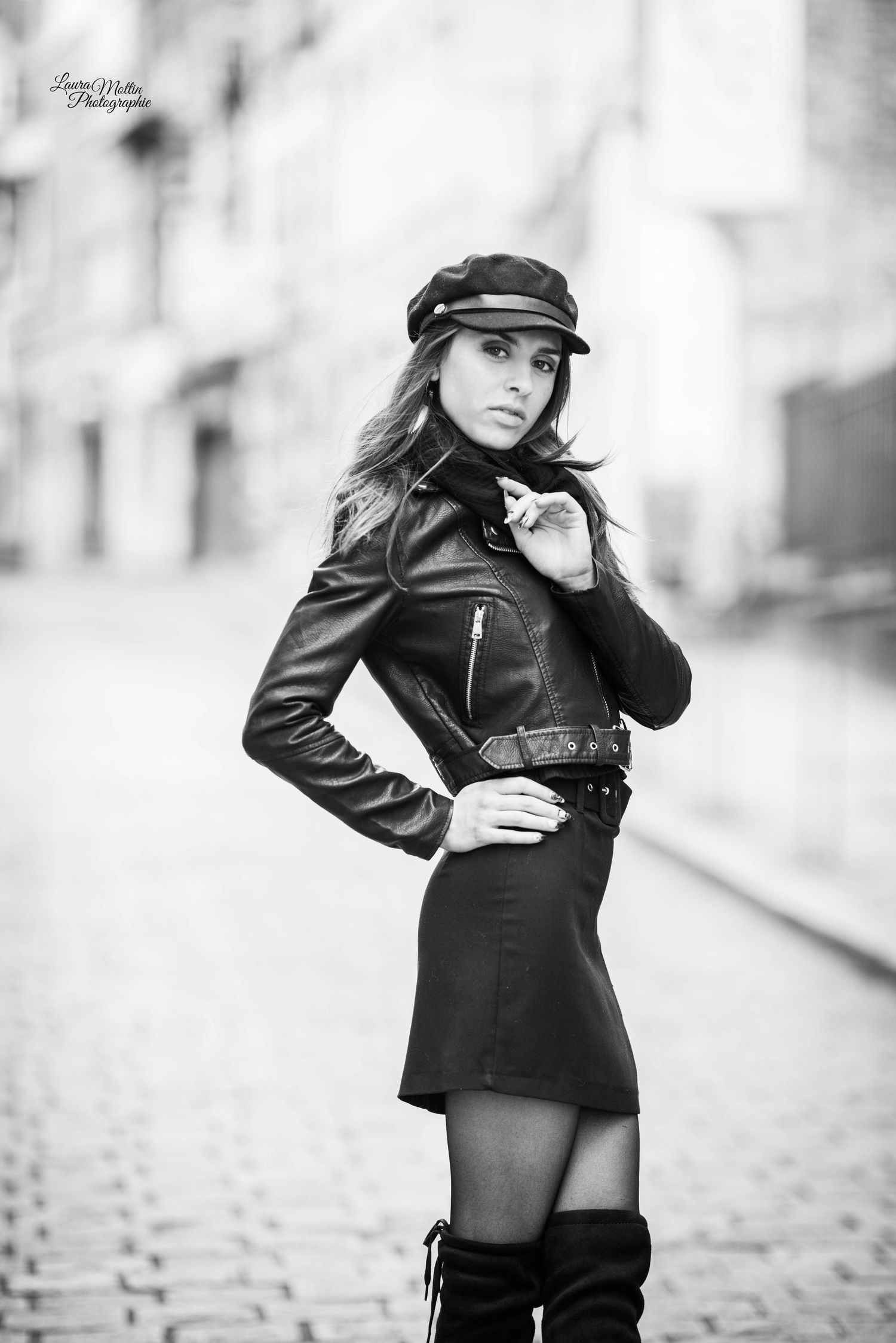 Black and white fashion portraits in leather jacket and cap on cobblestone street.