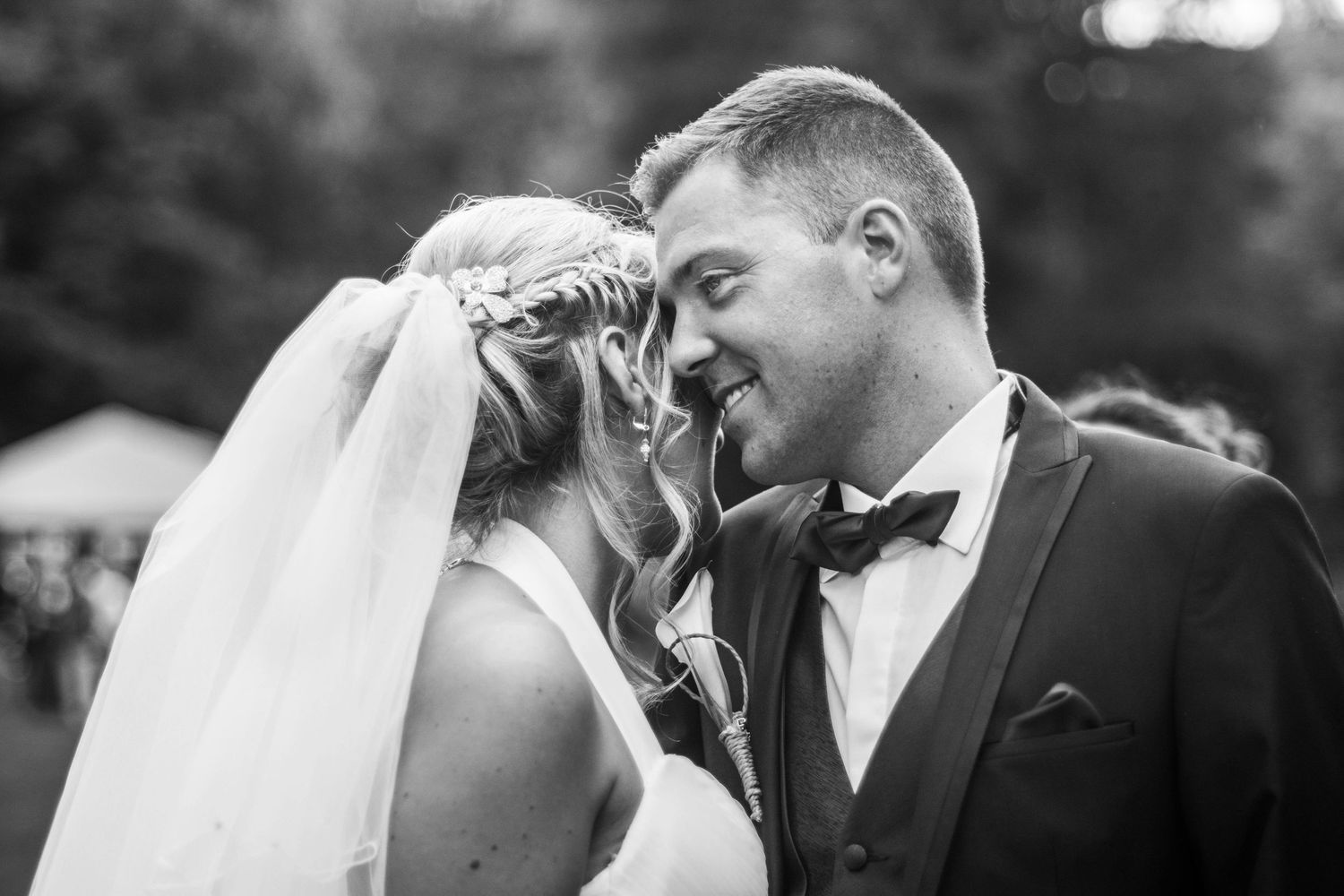 Black and white portrait captures romantic moment between couple in formal wedding attire.