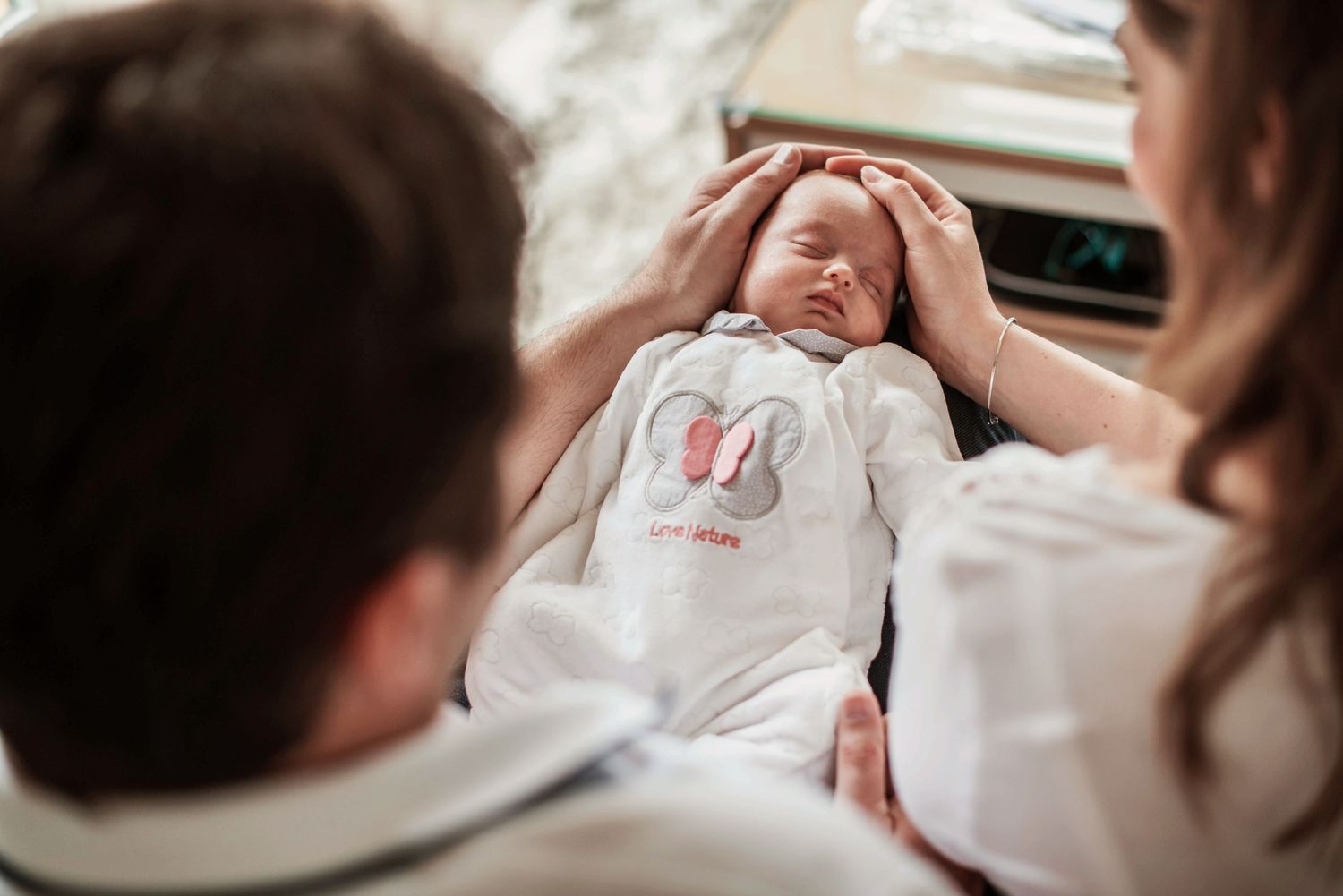 Parents sharing tender moments with sleeping newborn.