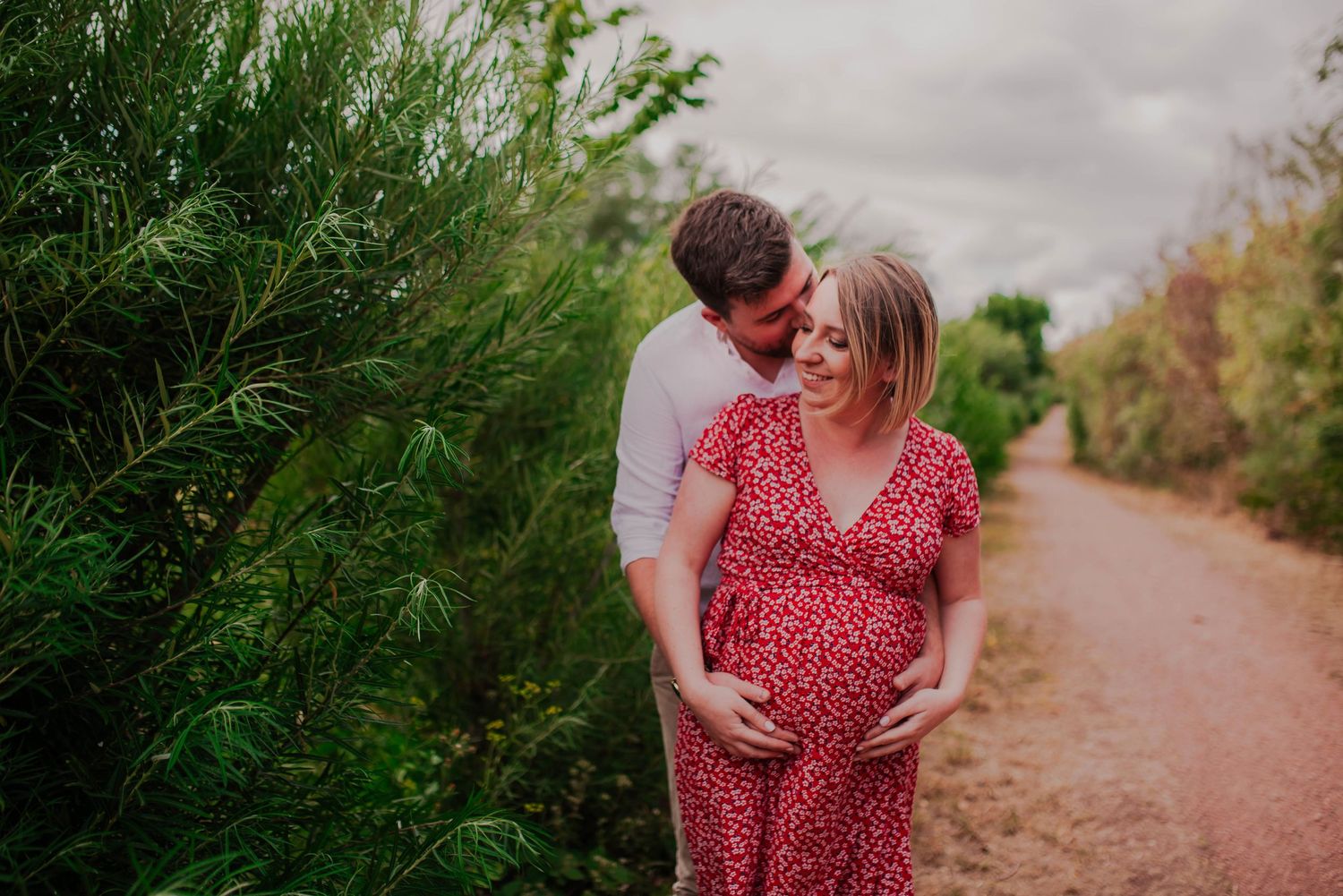Romantic maternity photos on a nature path in a red polka dot dress.