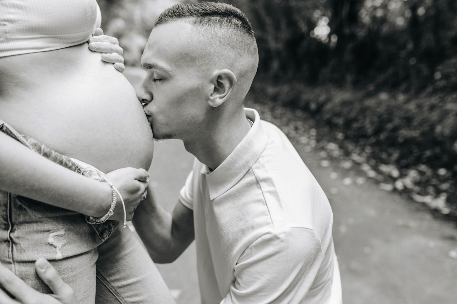 An intimate black and white maternity photo showing a tender moment with an expectant mother.