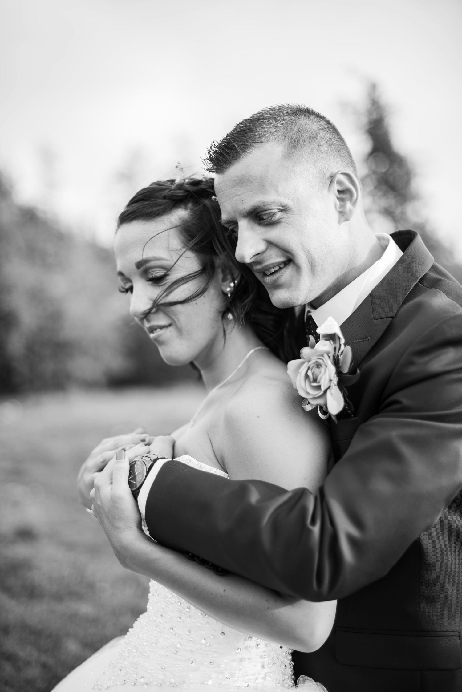 An intimate black and white portrait of newlyweds sharing a tender moment outdoors.