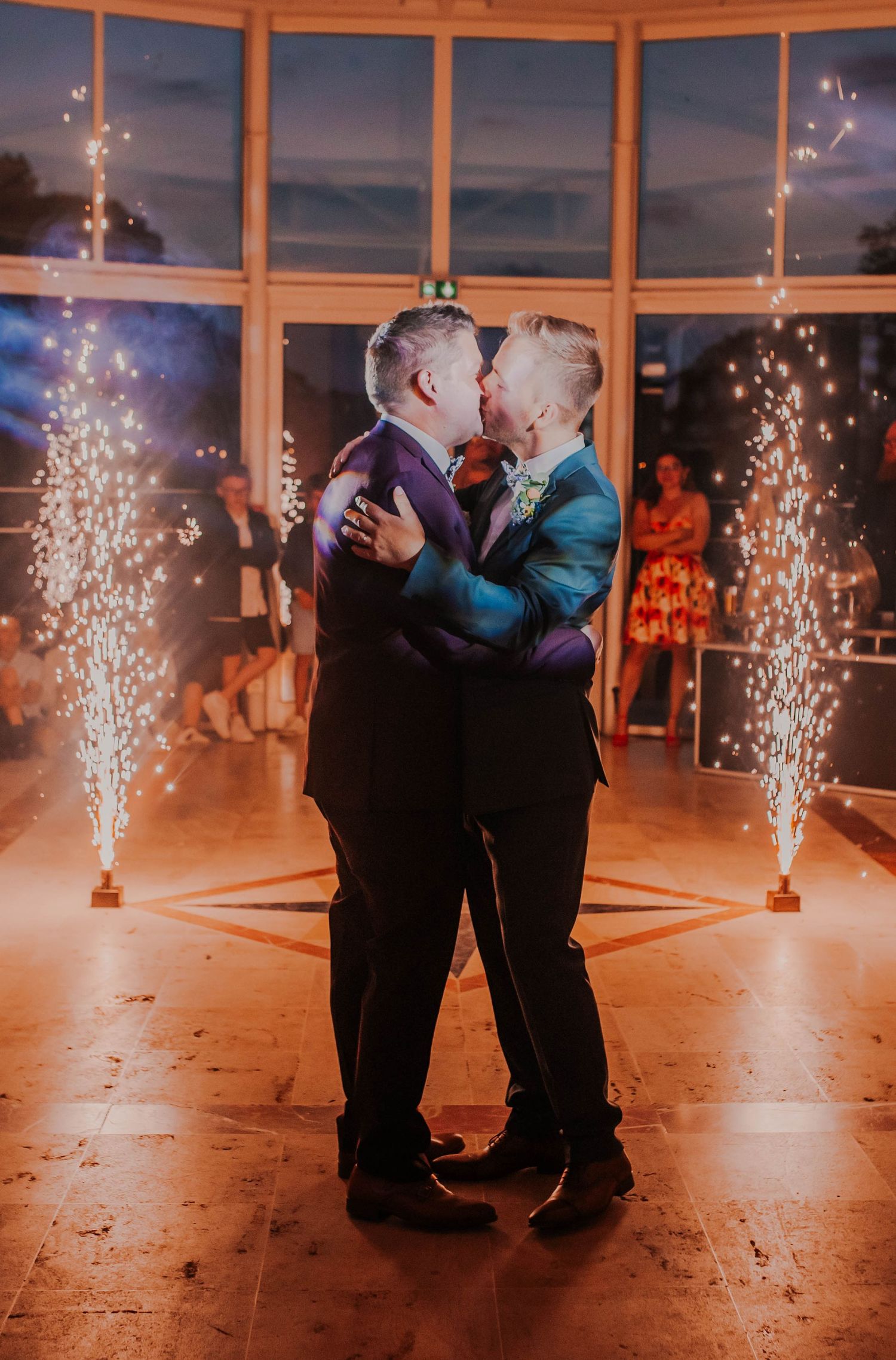 A couple shares their first dance surrounded by sparklers in an elegant reception venue.