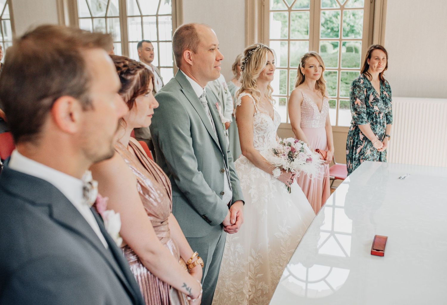 Wedding ceremony in an elegant room with arched windows and formal attire.