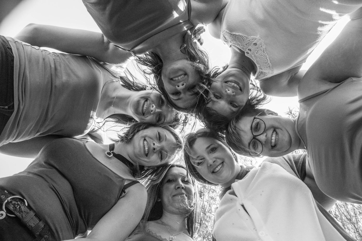 Group lying in circle formation on grass creating artistic overhead shot.