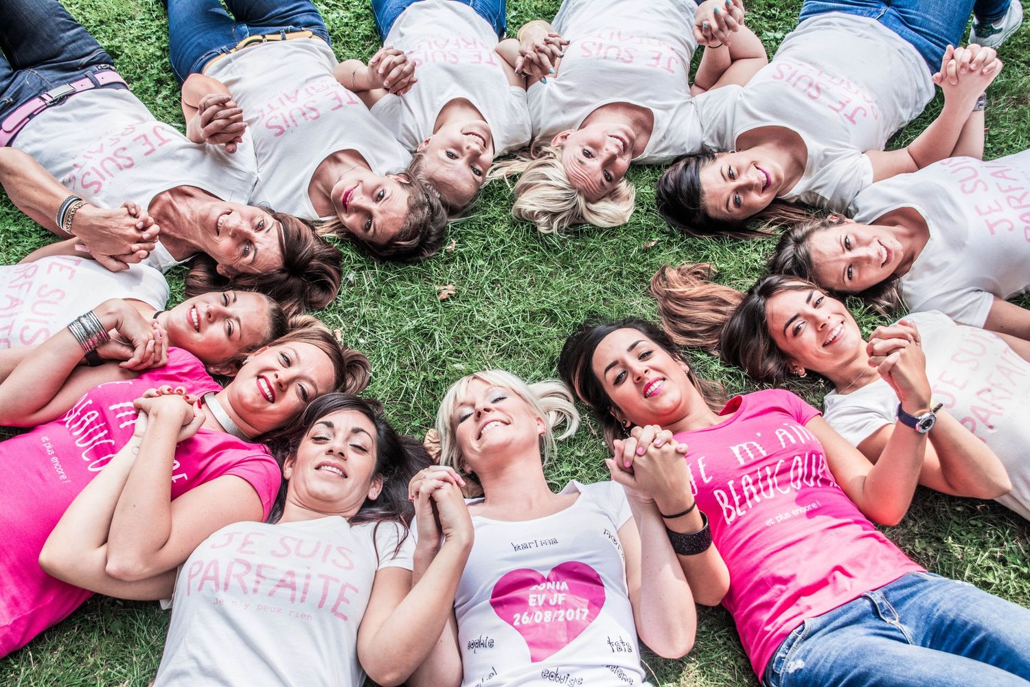 Friends lying in circle formation on grass making silly expressions.