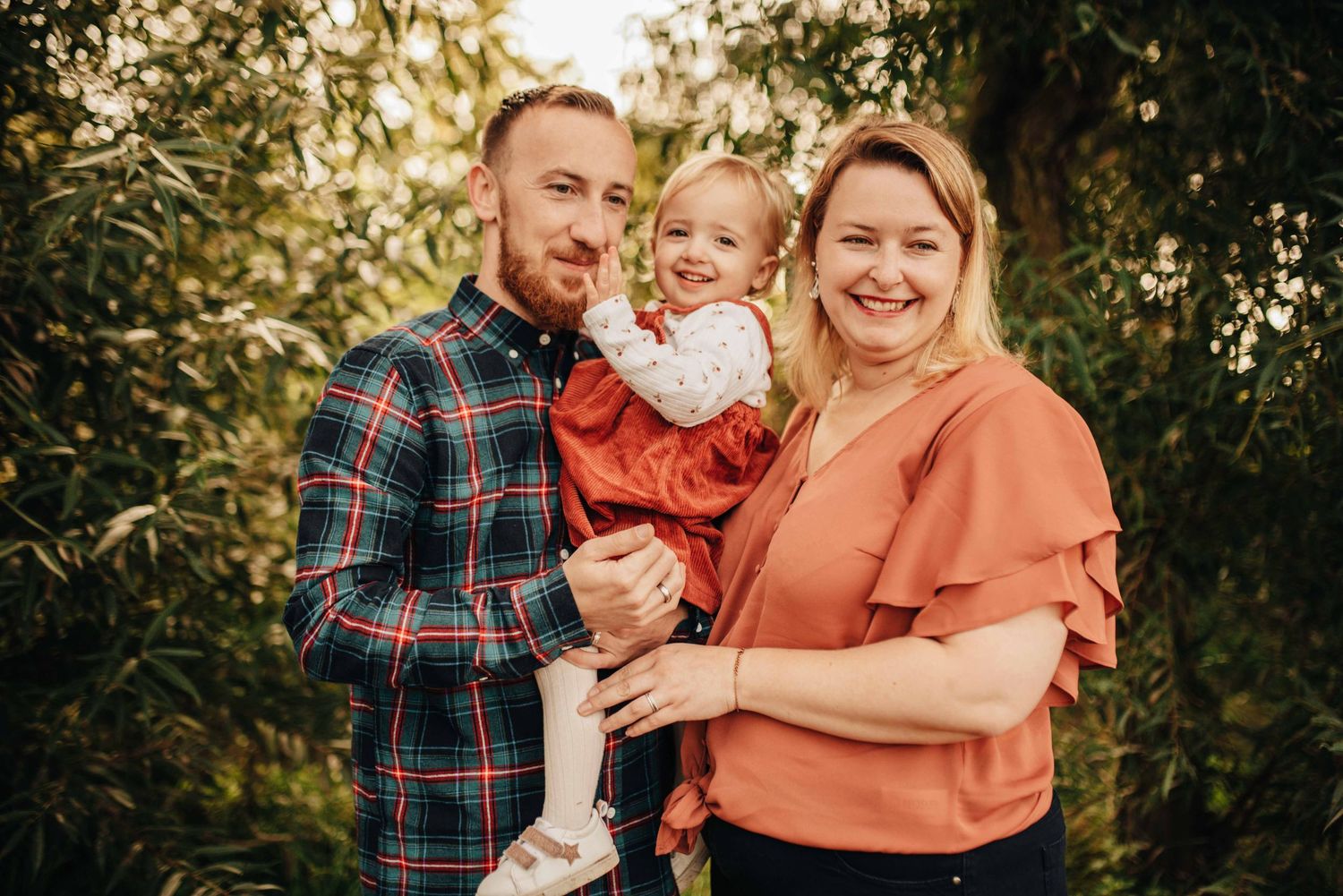 Casual family photoshoot in autumn setting with plaid and rust-colored clothing.