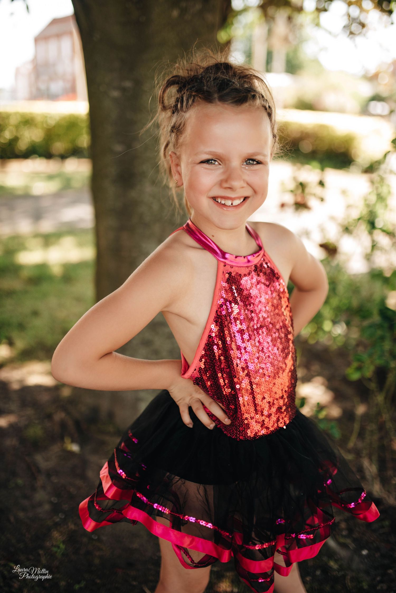 Dance portrait featuring sparkly red and black tutu costume in natural outdoor setting.