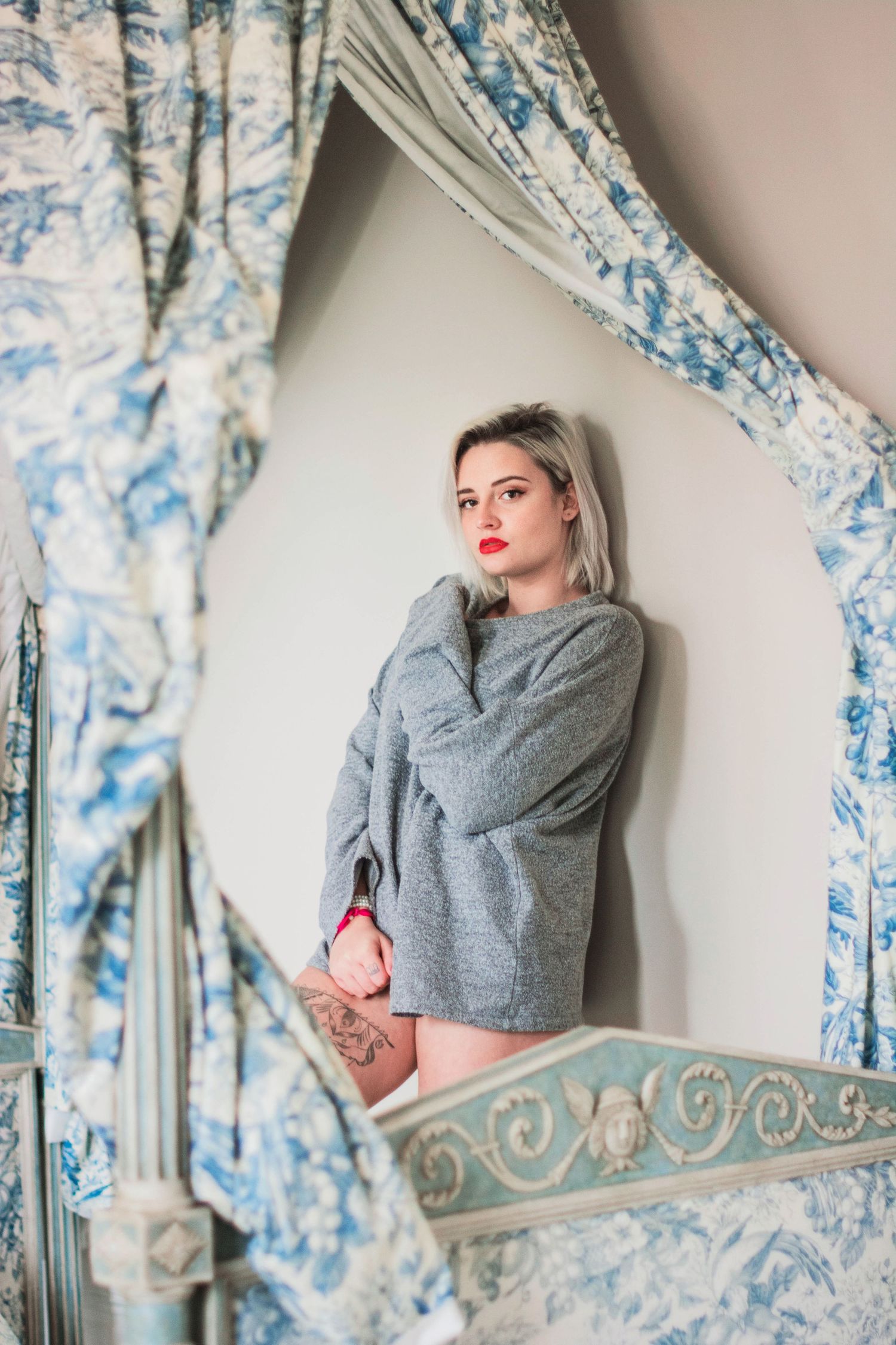 Fashion portrait series with model in grey sweater against floral curtain backdrop.