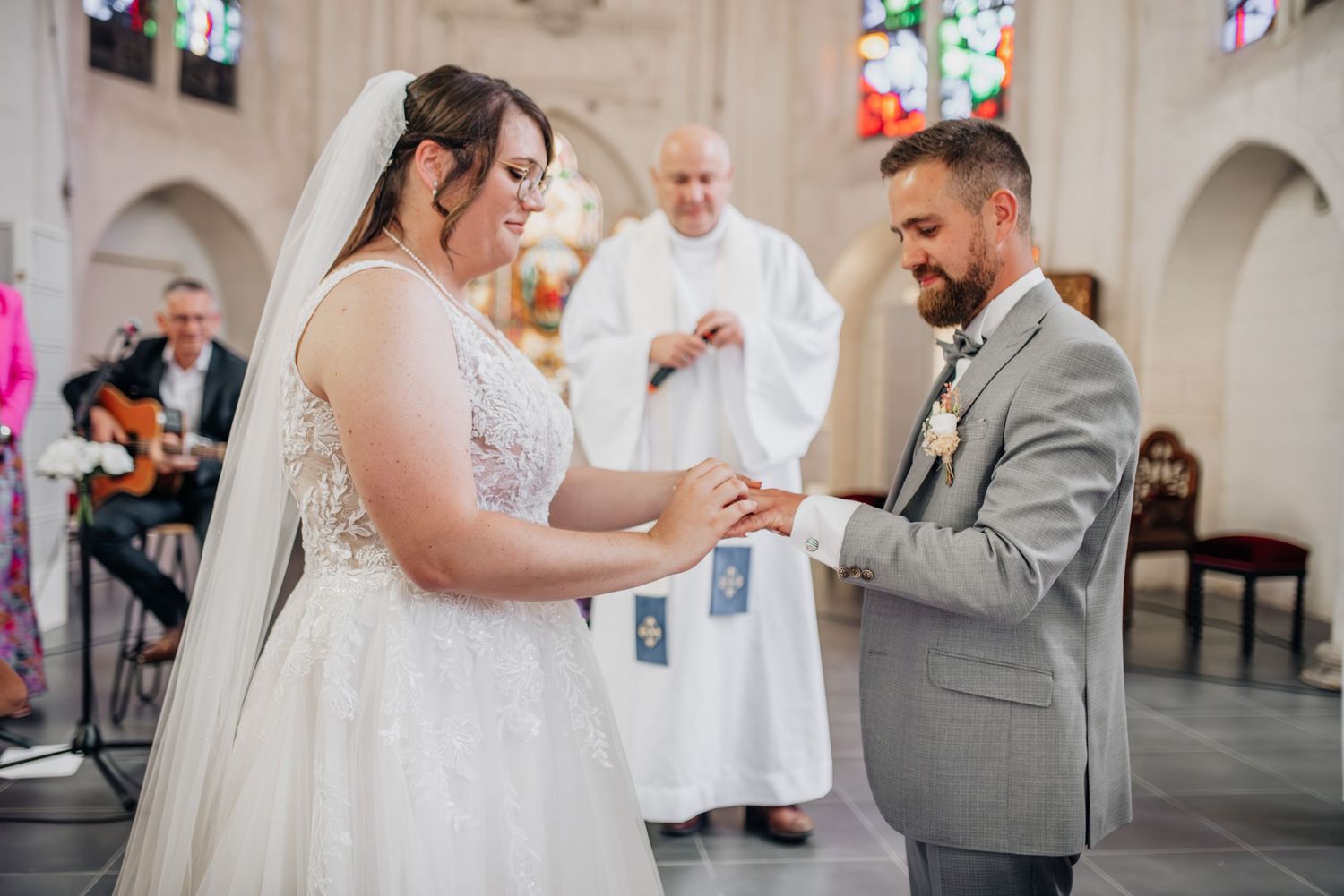 A romantic wedding ceremony takes place in a beautiful church with stained glass windows and gothic arches.