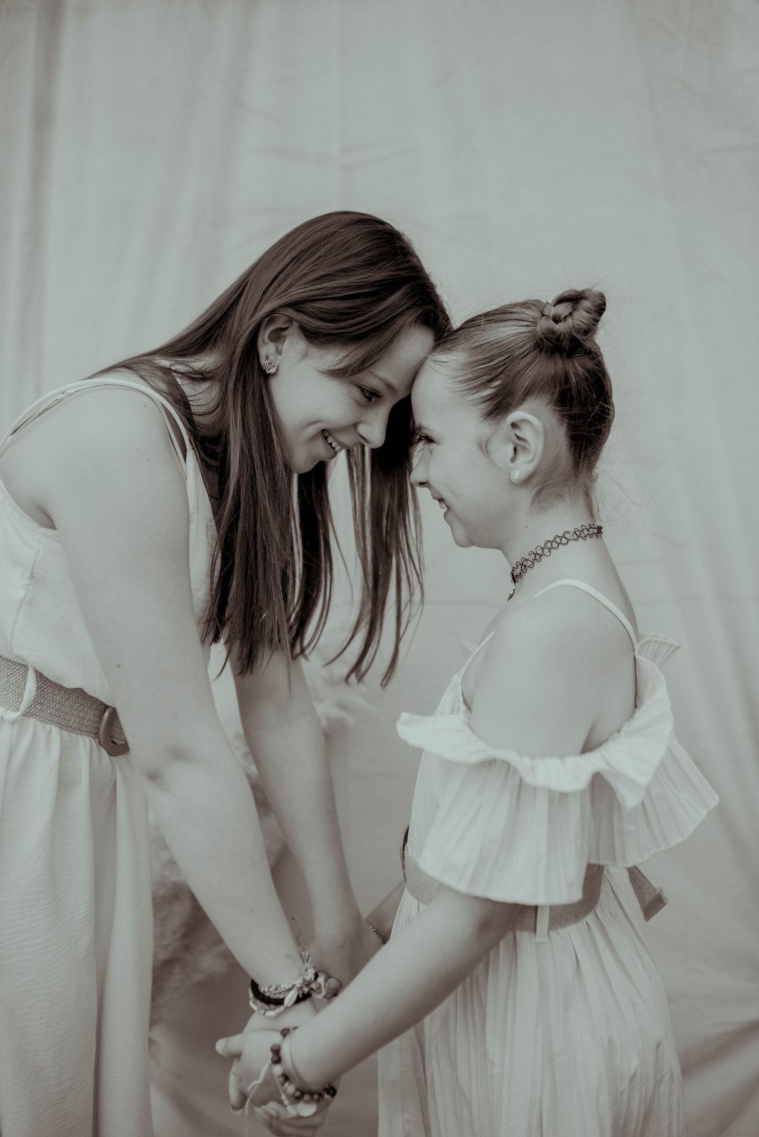 A tender black and white portrait series showing intimate moments between two people in white dresses.