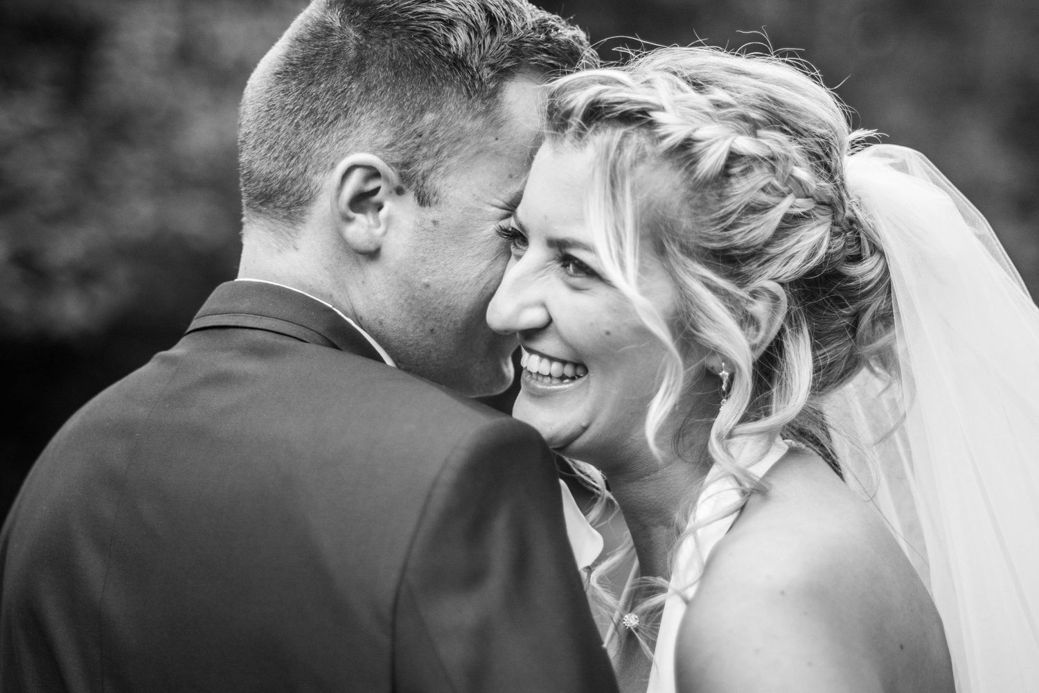 Intimate black and white moment captured between newlyweds sharing a tender embrace.
