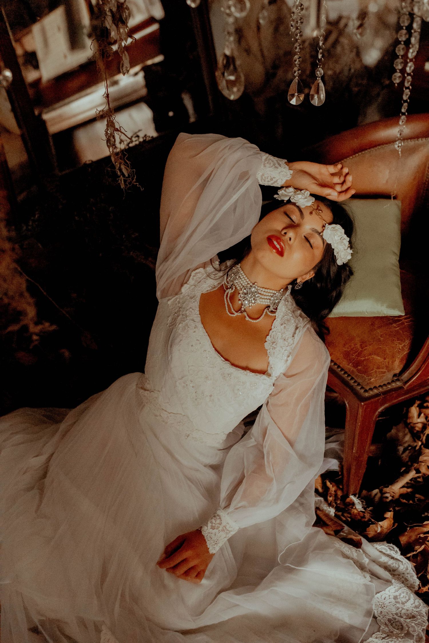 Romantic vintage-styled portrait with white lace dress and crystal chandelier details.