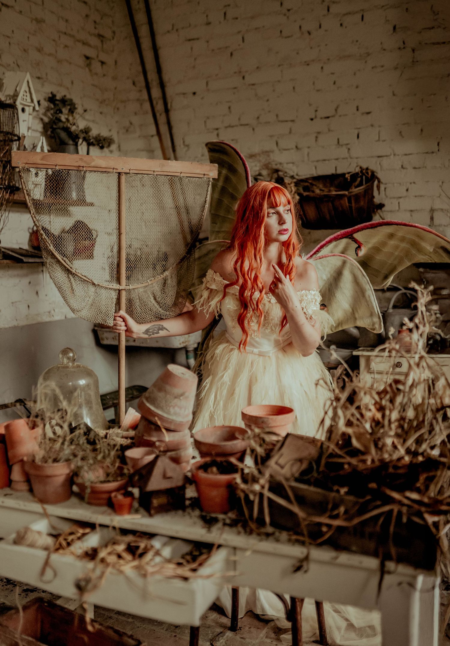 Whimsical indoor scene with pink hair and fairy wings against brick wall.