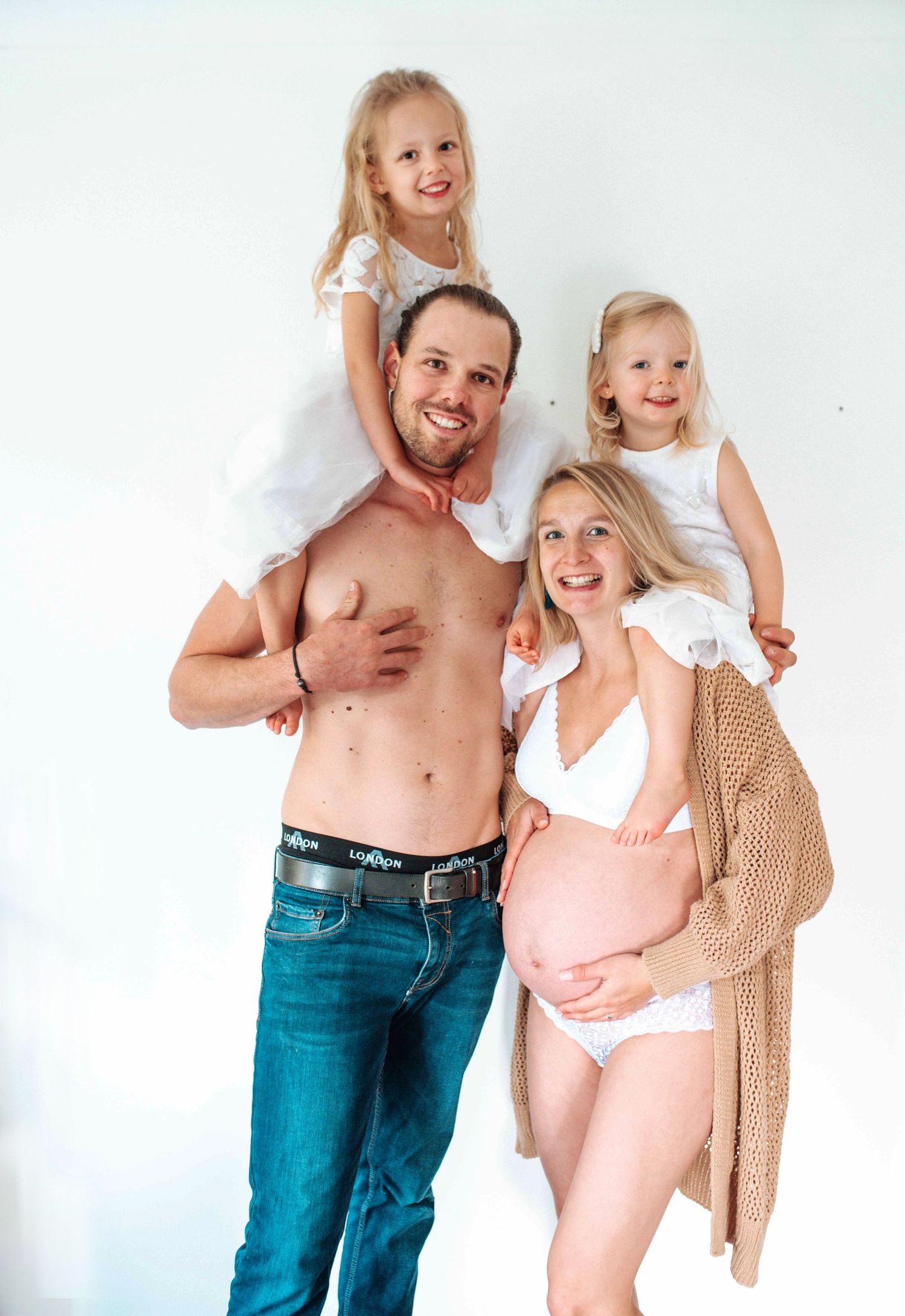 A casual family photo session against a white studio backdrop showing playful interactions.