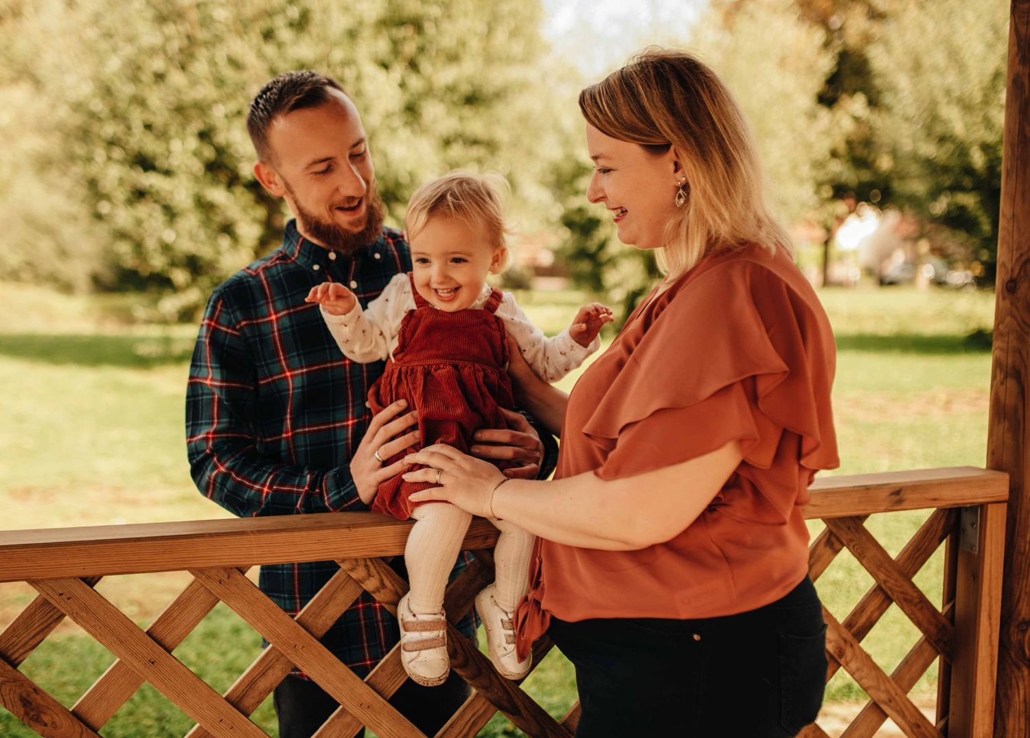 Family portrait session on wooden deck during golden hour with toddler.