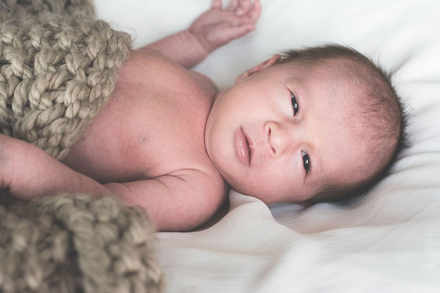 Series of intimate black and white photos showing a newborn's tiny feet cradled in gentle hands.