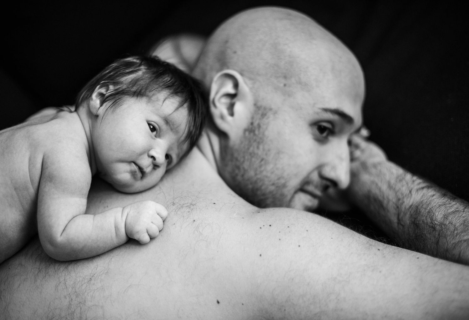 Intimate black and white series showing tender moments between parent and sleeping baby.
