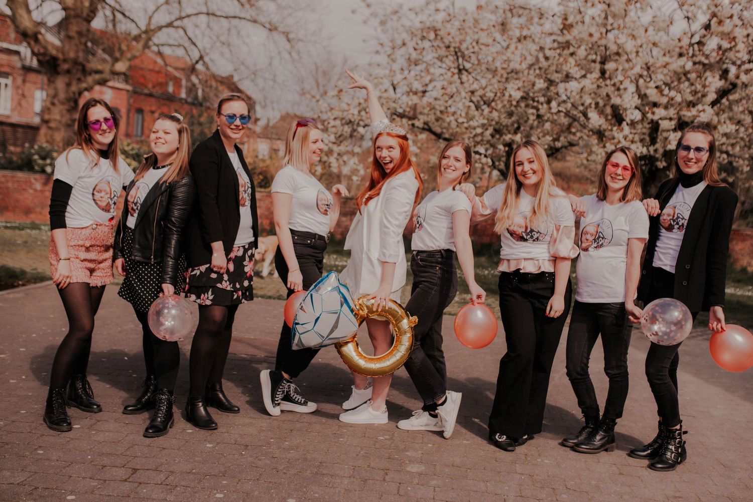 A group photo of friends in coordinated outfits posing under spring blossoms at sunset.