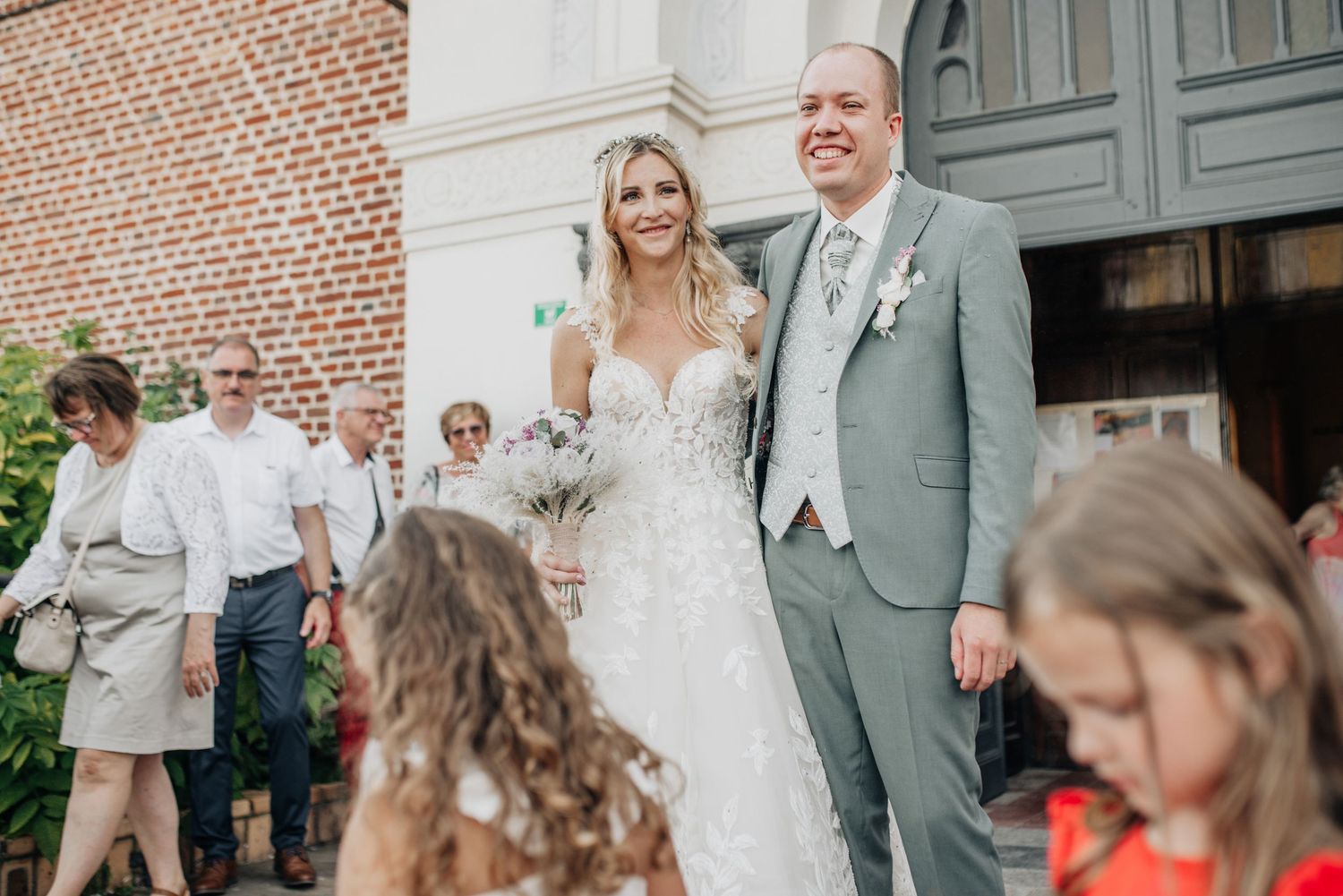 Wedding party gathered outside brick church entrance.