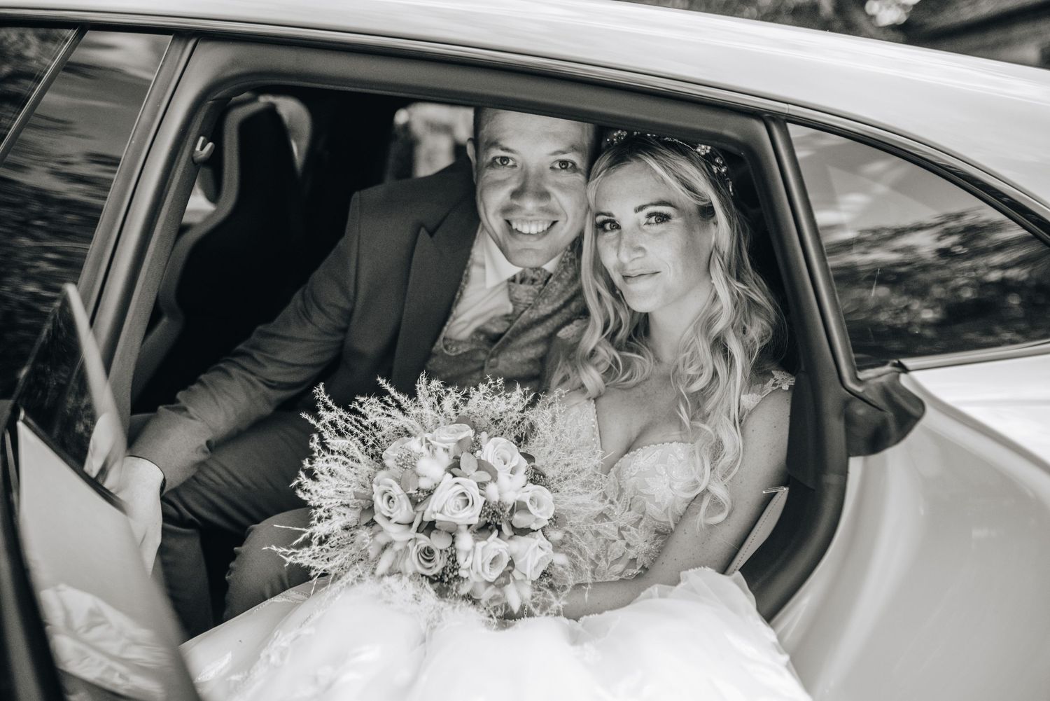 Wedding couple sharing moment in classic car in black and white.