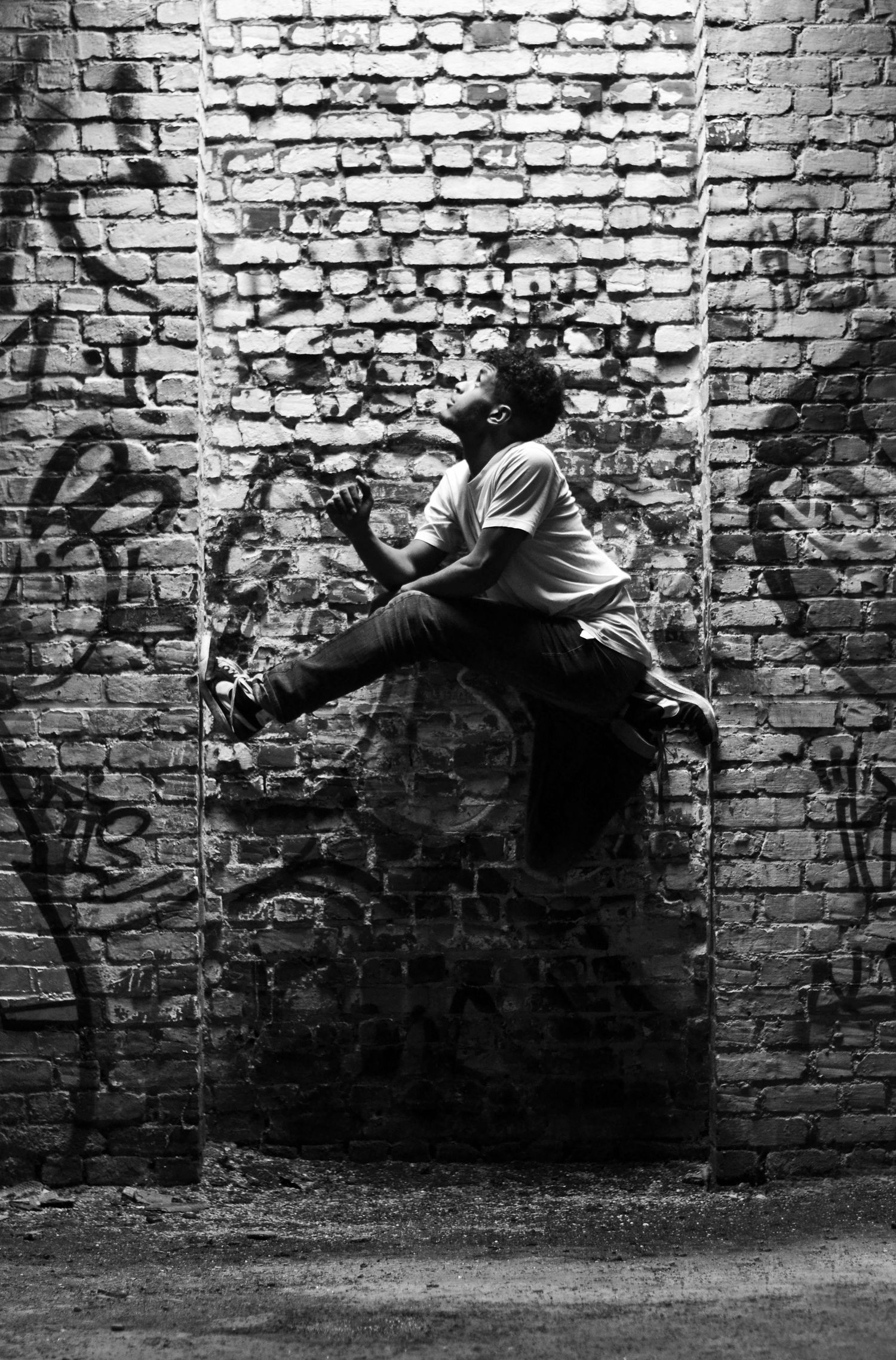 Black and white sequence showing dynamic movement against weathered brick wall.