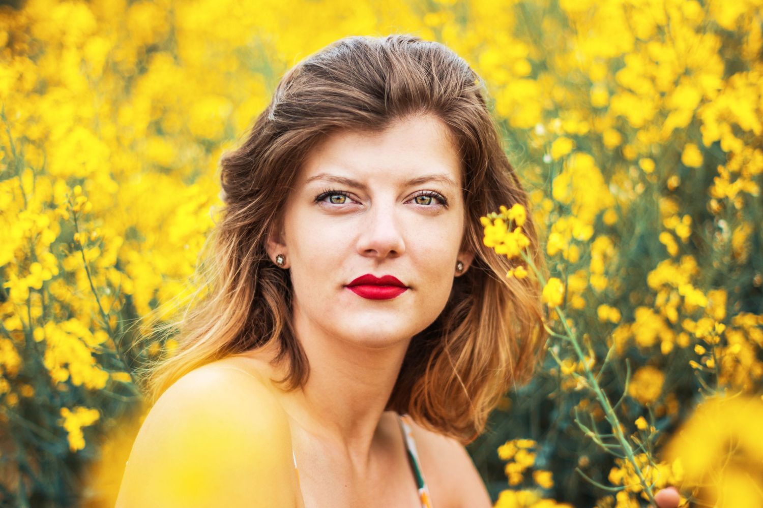 Portrait against vibrant yellow flowers in natural outdoor setting.