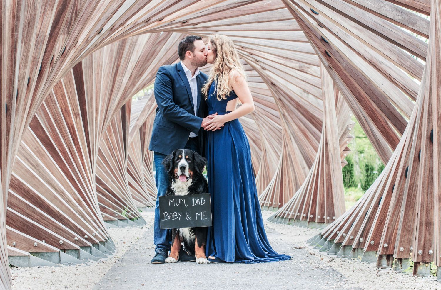 Romantic couple photos taken under a wooden architectural structure with repeating beams.