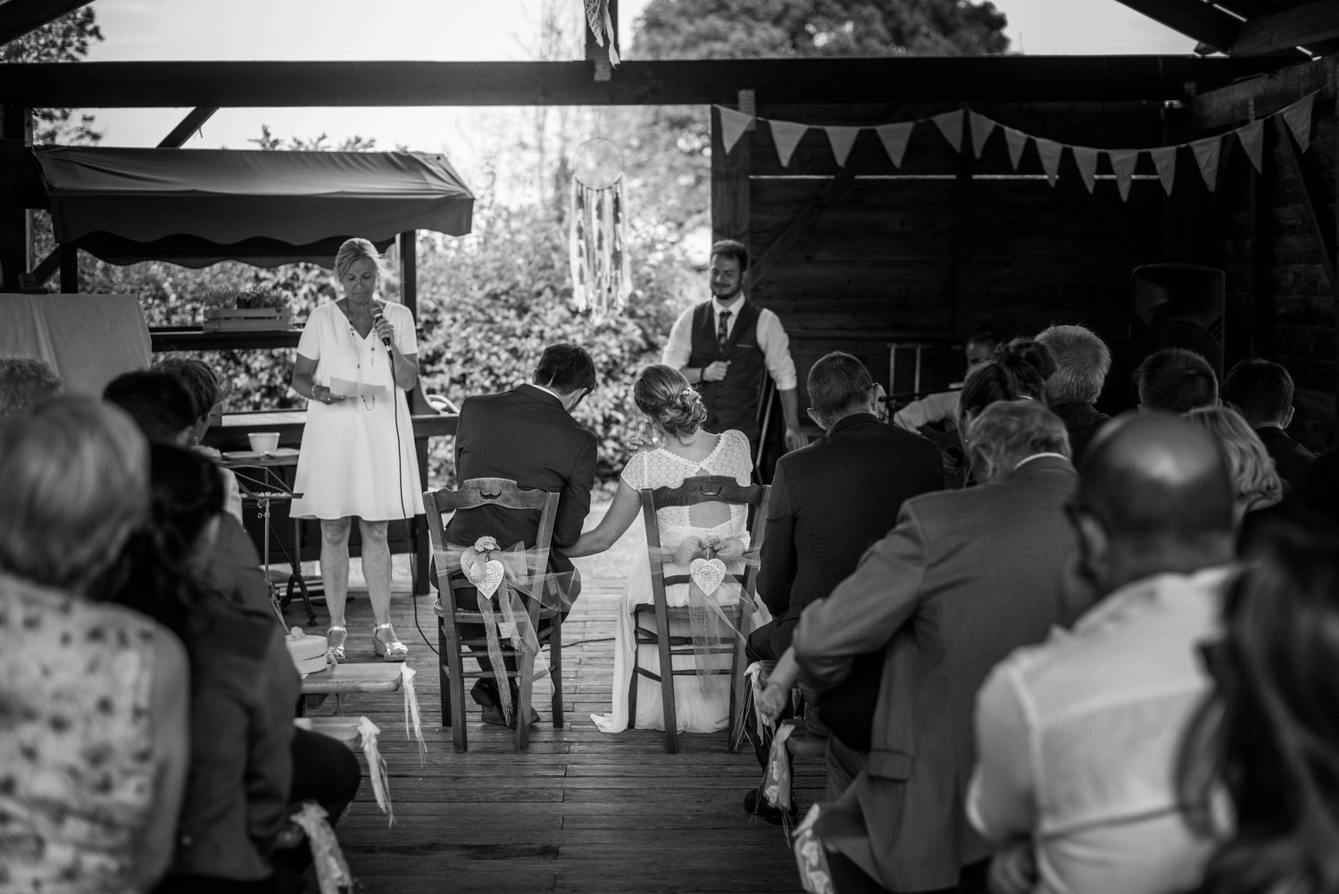 An outdoor wedding ceremony with guests seated under bunting decorations.