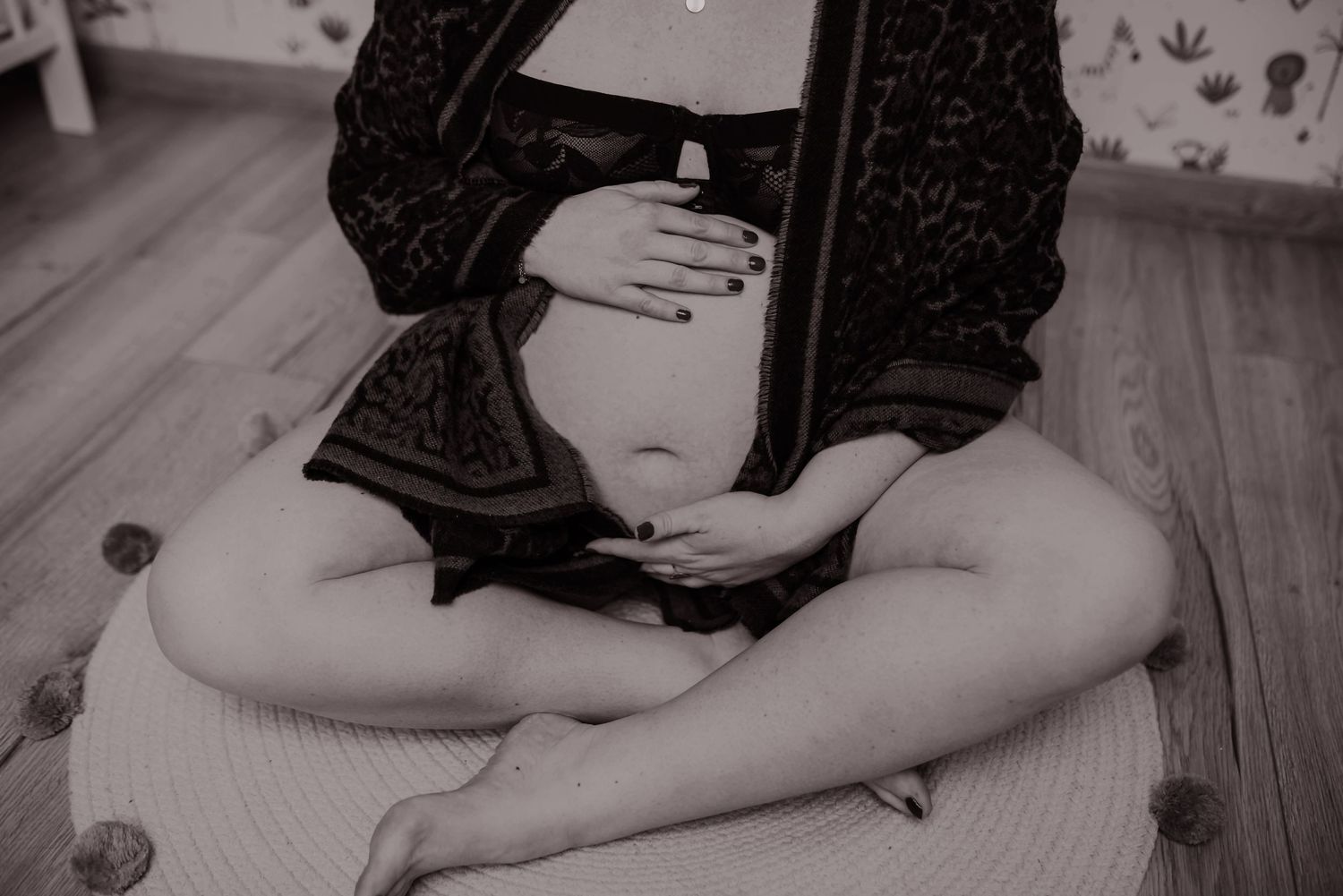 Black and white artistic maternity photo with soft natural lighting.