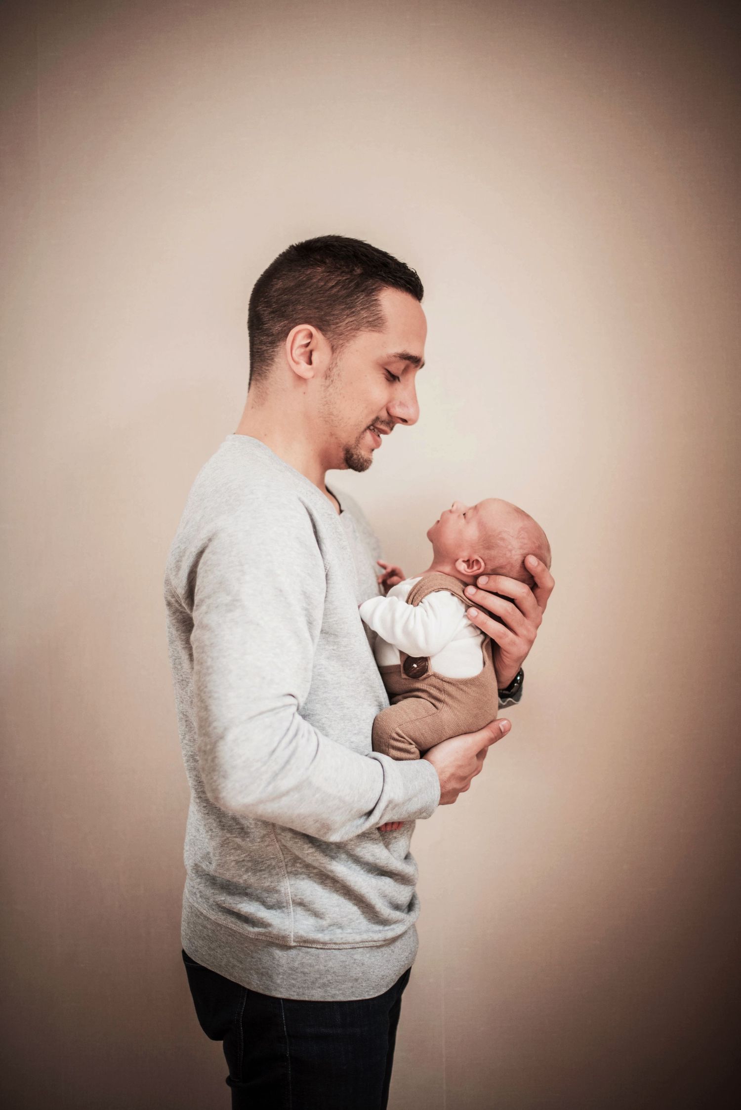 Heartwarming sequence showing parent bonding with newborn against neutral background.