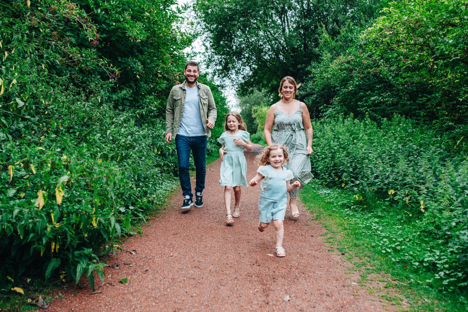 Family strolling along a dirt path surrounded by vibrant green foliage.