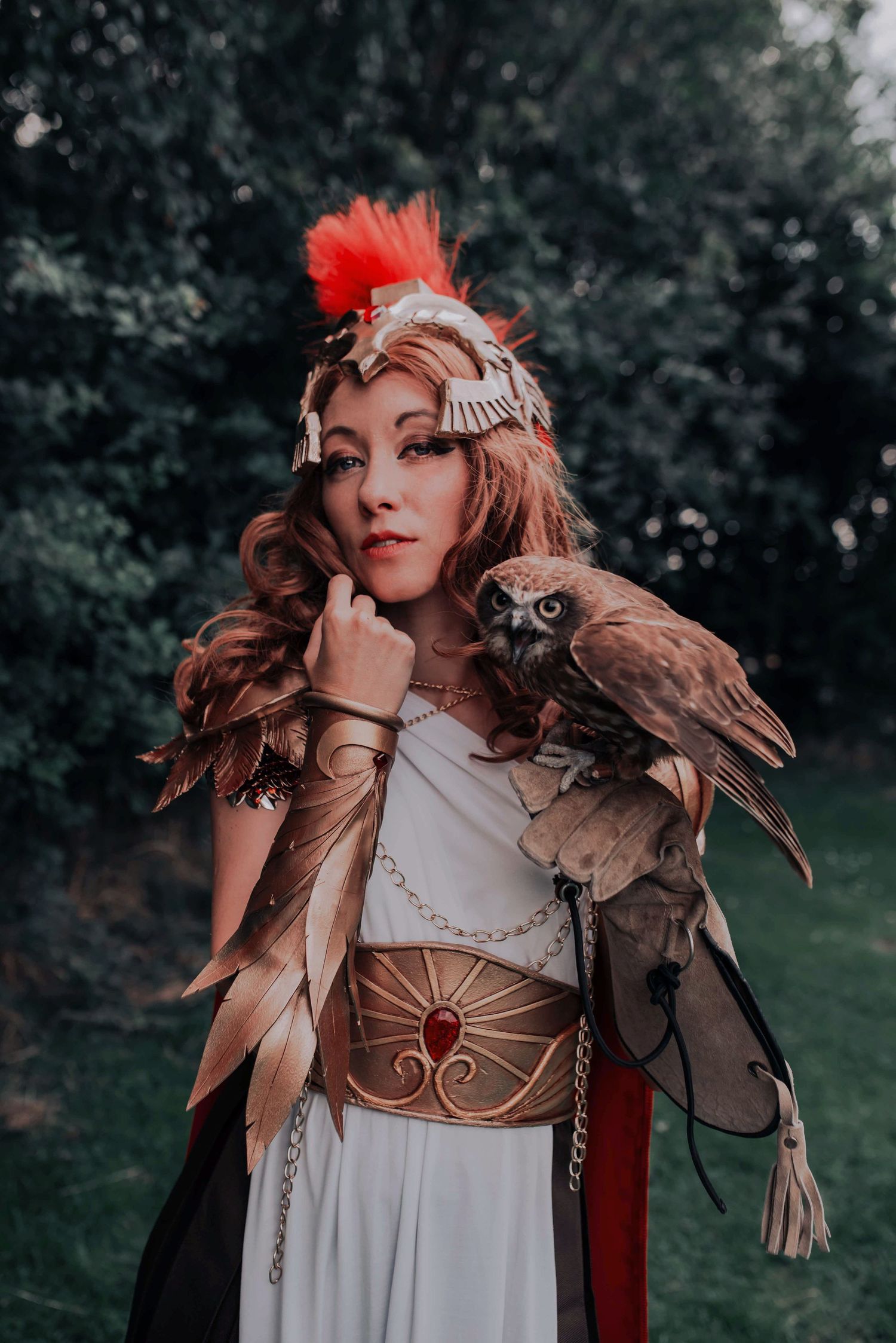 Fantasy-themed costume shoot featuring feathered headdress and medieval-inspired dress in outdoor setting.