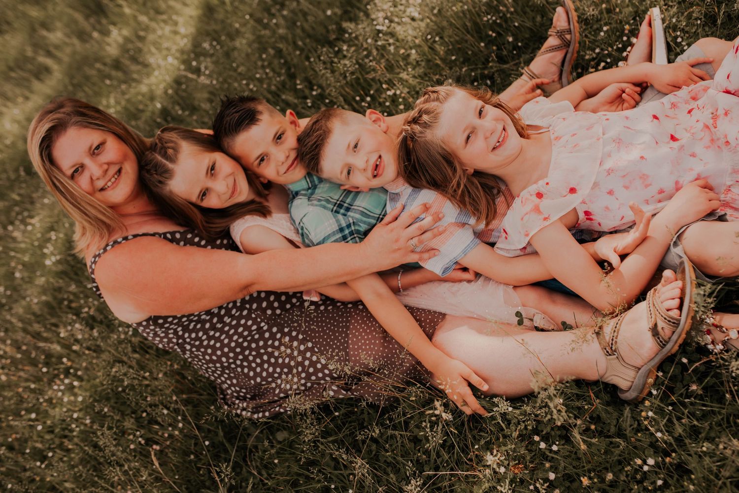 Family members lying close together on grass during a warm summer photoshoot.