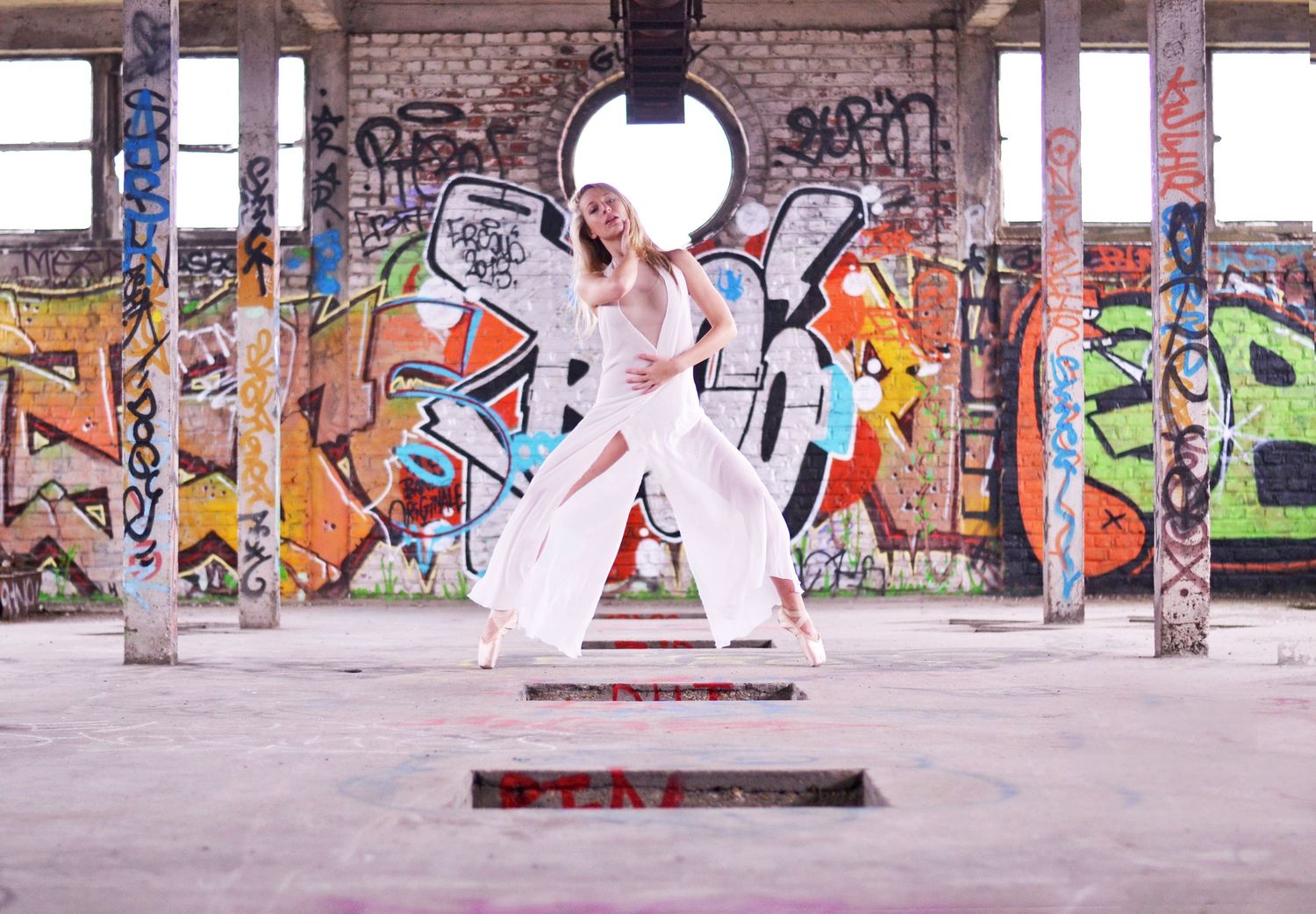 Wide panoramic view of urban space with colorful graffiti murals on brick walls.