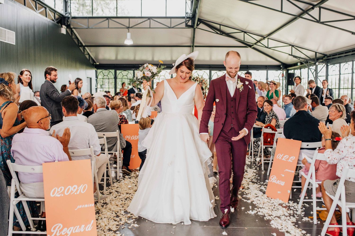 A joyful wedding ceremony exit with guests lining the aisle in an industrial-style venue.