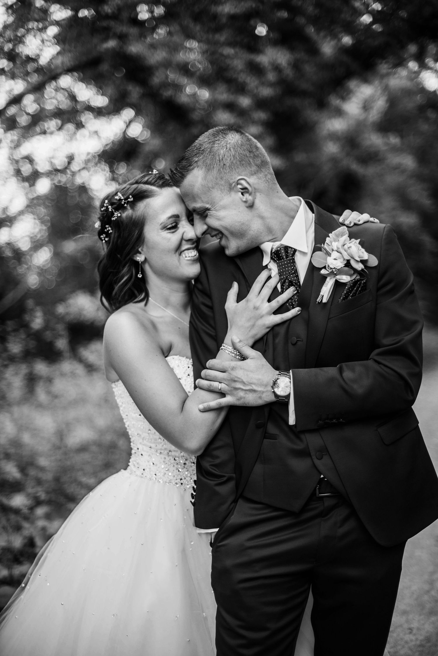 An intimate black and white portrait of newlyweds sharing a tender moment in a garden setting.