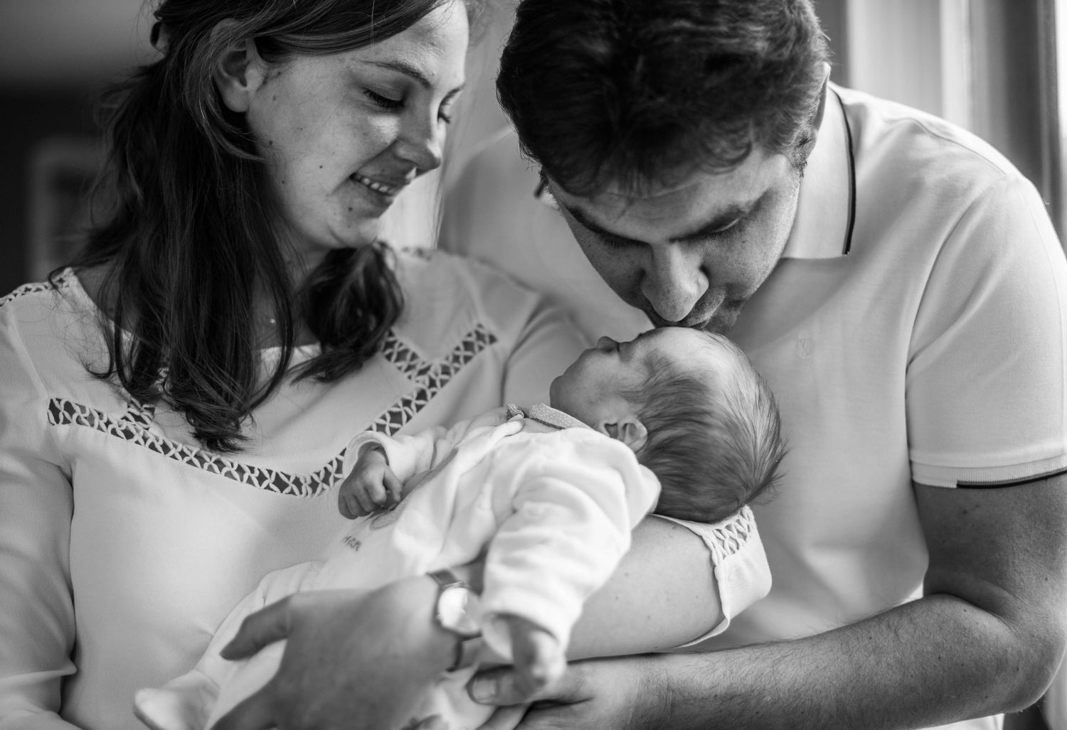 Black and white portrait of parents bonding with newborn.