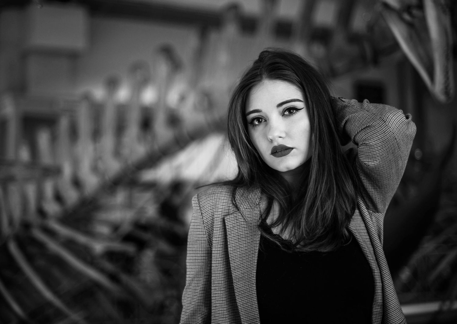Moody black and white portrait featuring grey blazer in architectural setting.