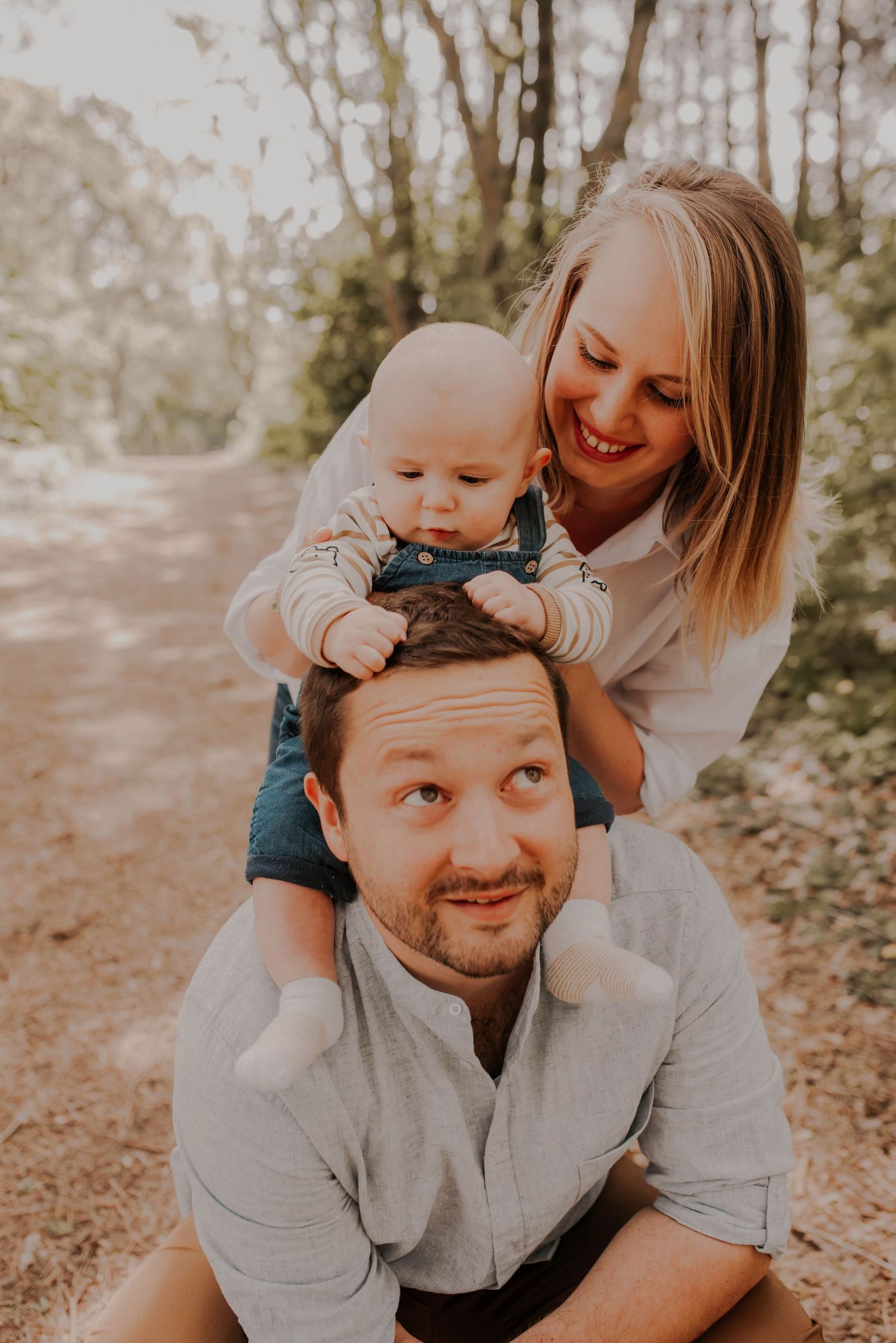 Playful family photography session with natural poses in a wooded setting.