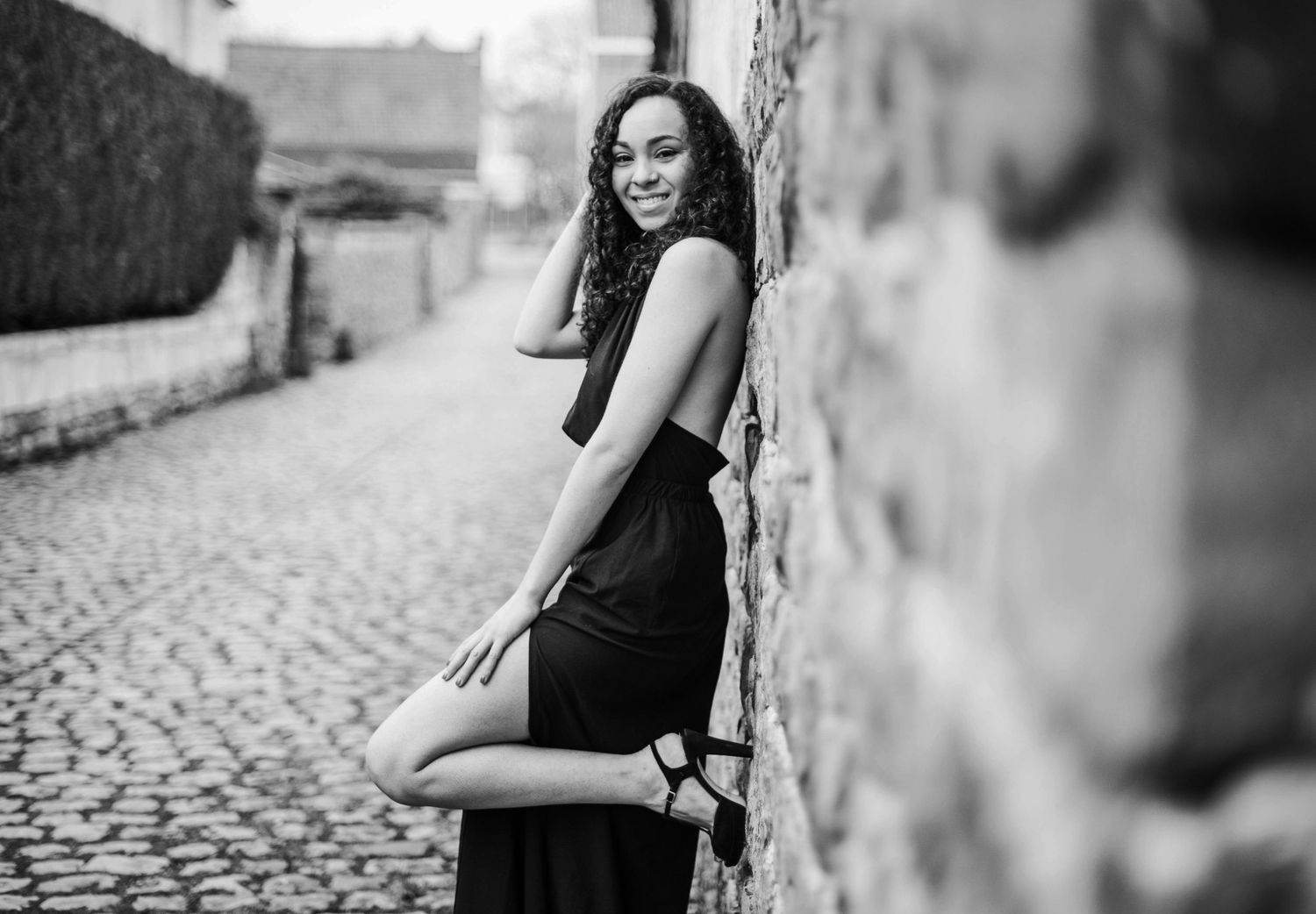 Black and white portrait series showing a woman in a casual pose against a textured wall background.