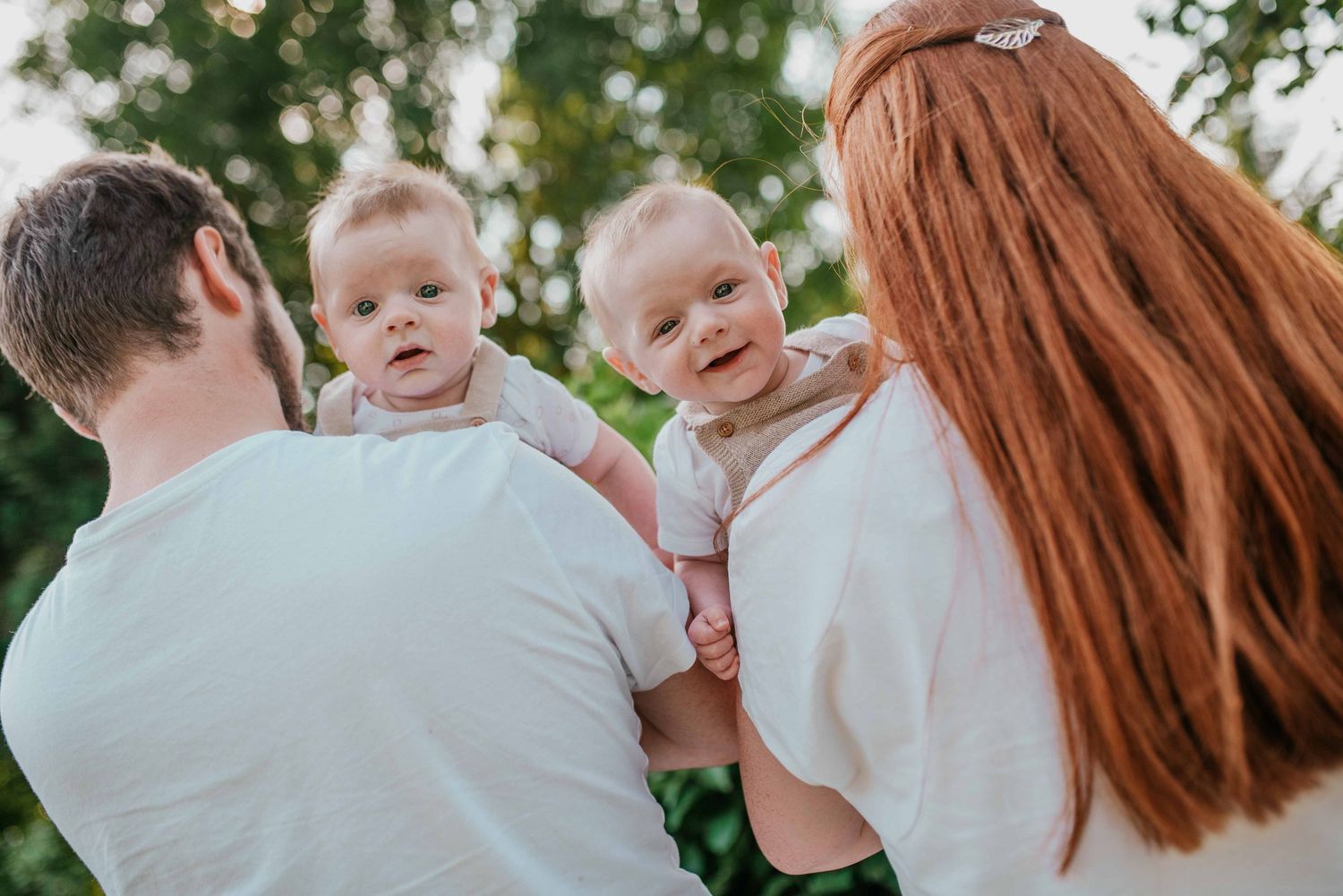 Family wearing white clothing poses together for outdoor portrait session.