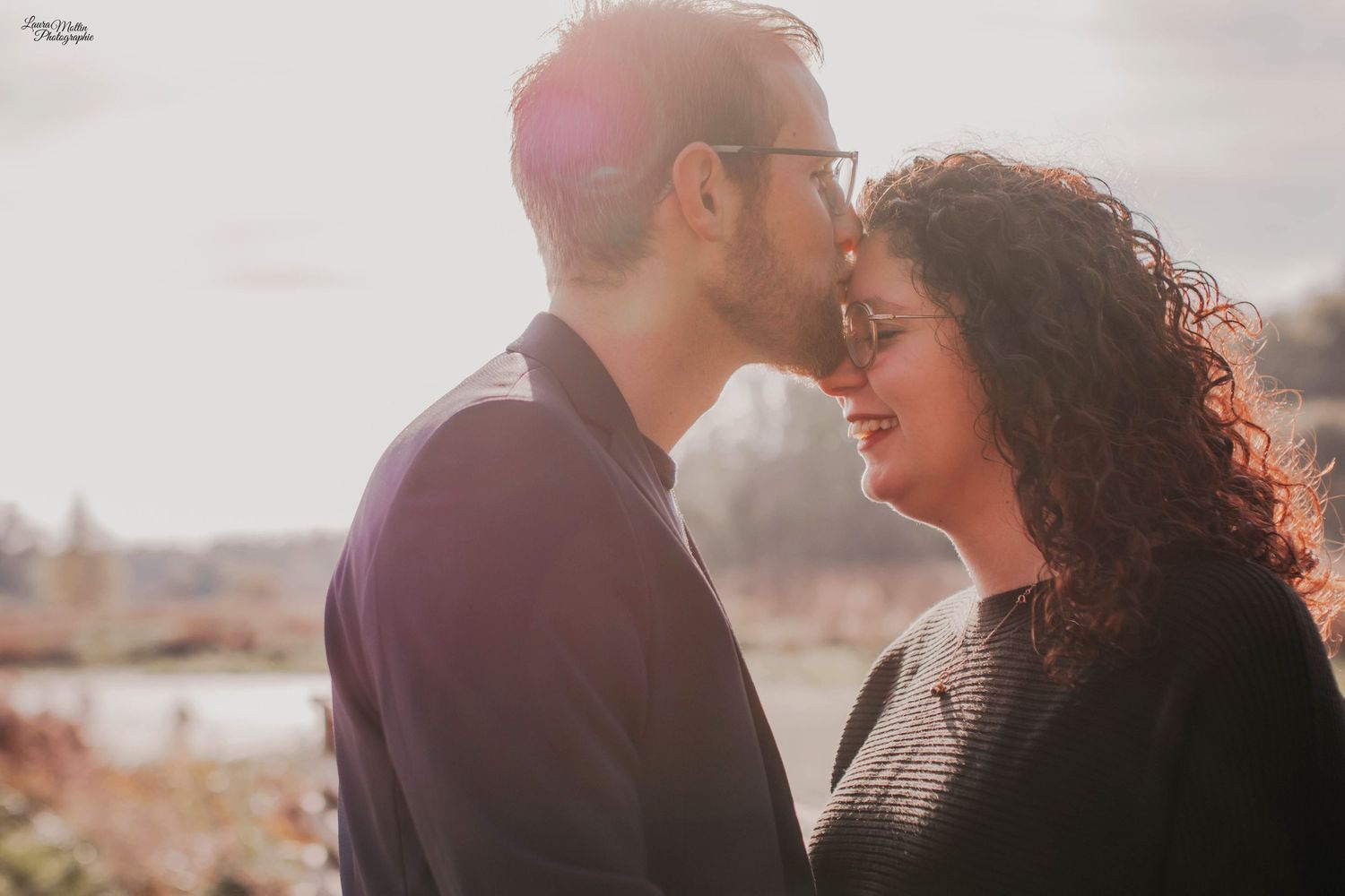 Tender moment between couple during golden hour with soft lighting and urban backdrop.
