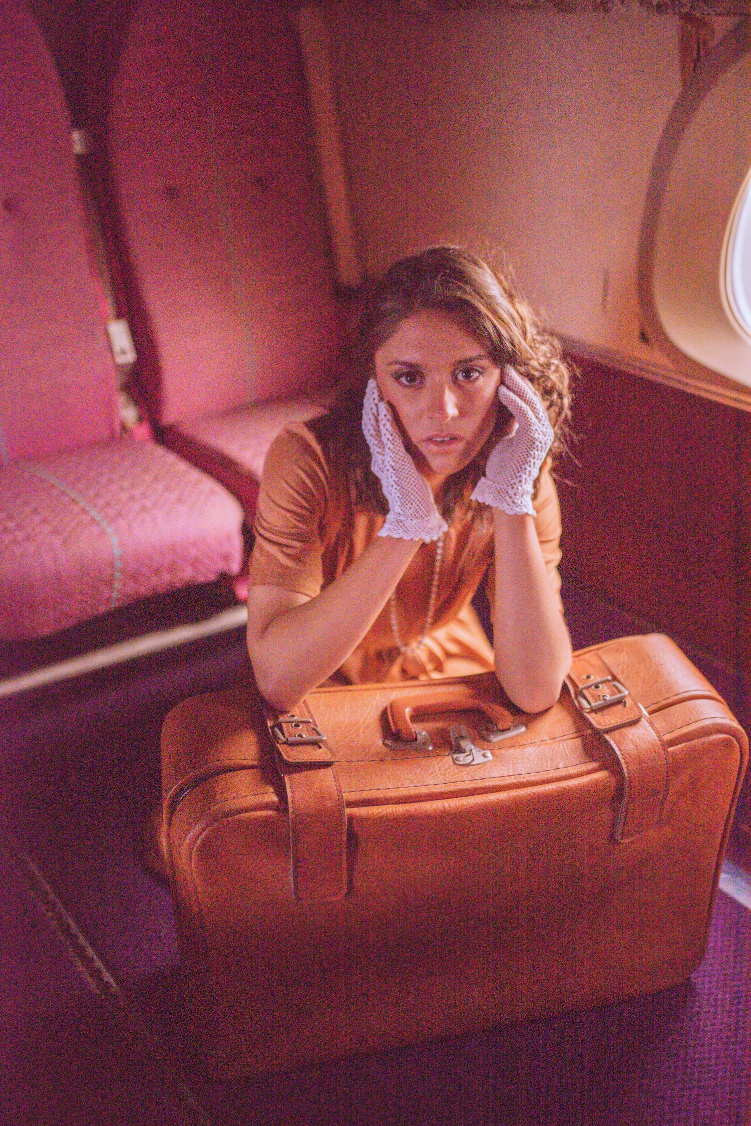 Artistic sequence of someone playfully posing with a vintage brown leather suitcase in warm lighting.