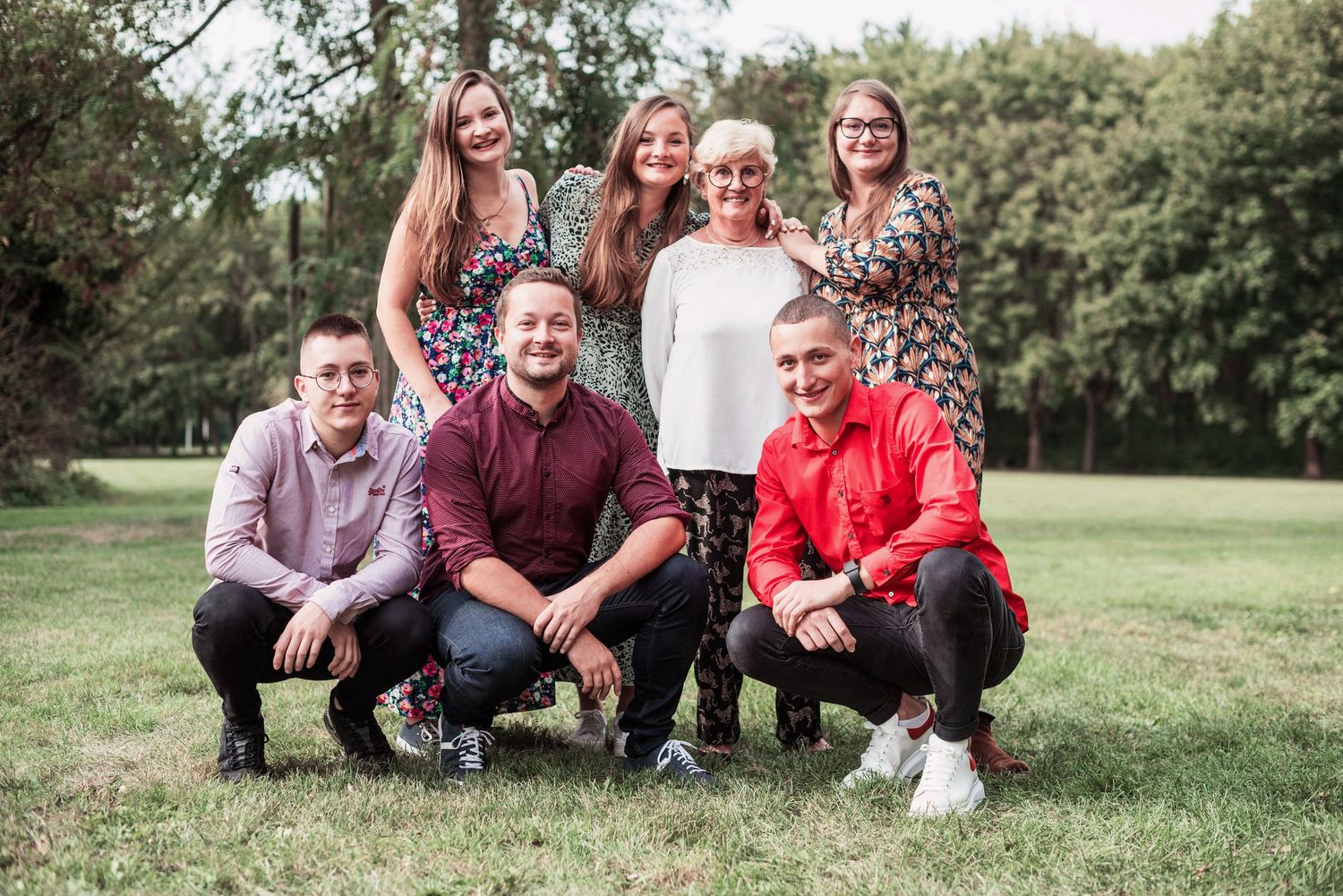 Extended family gathered for casual outdoor portrait session on grassy lawn.