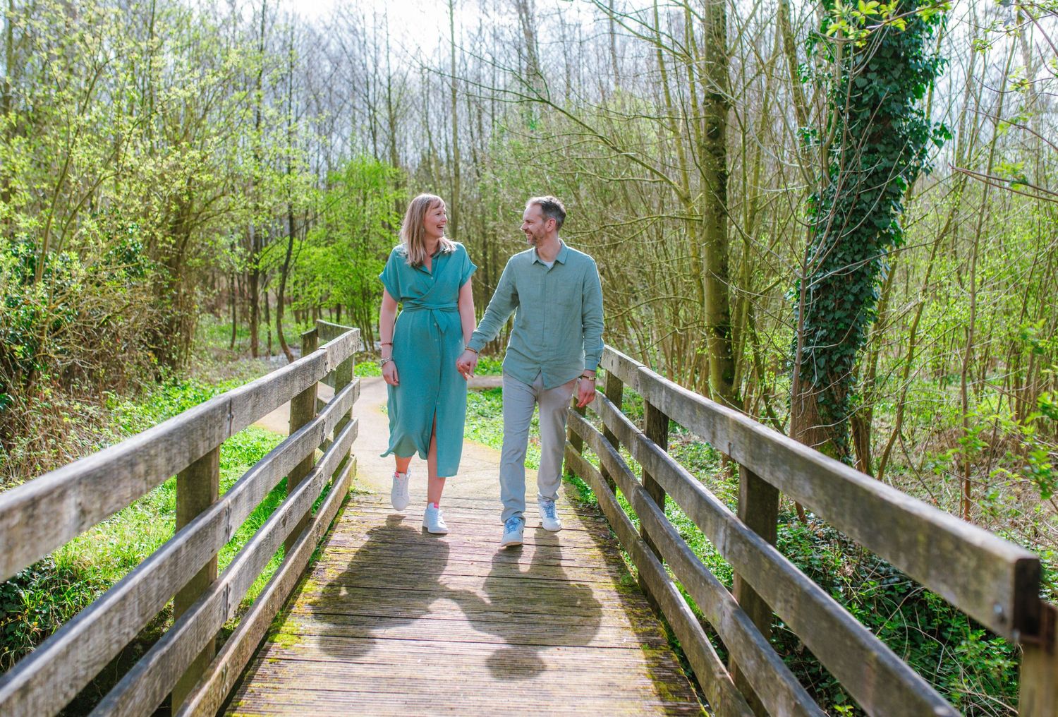 Series of photos showing two people walking along a wooden boardwalk through a forest.