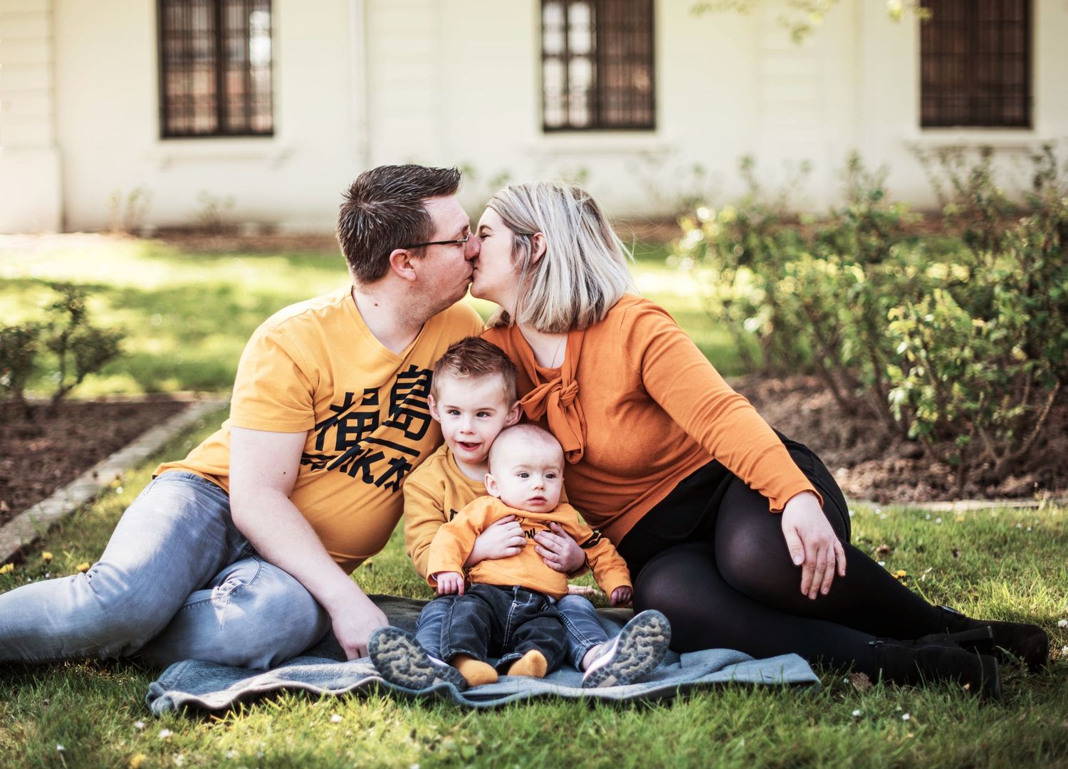 Family lifestyle session outside a white house with multiple casual poses.