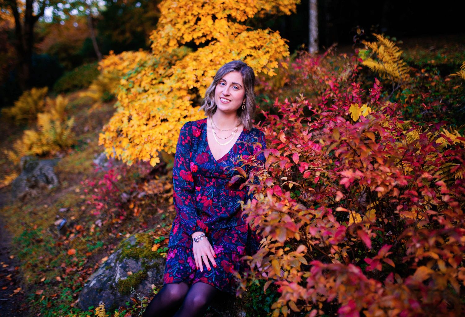 Autumn photoshoot with colorful fall foliage and purple floral dress.