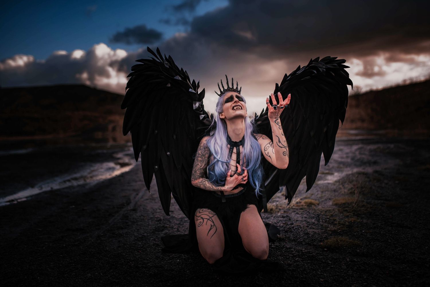 A dark fantasy themed photoshoot with black wings in twilight.