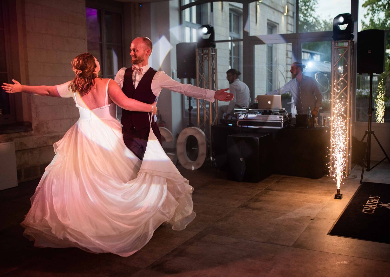 Romantic first dance at wedding reception with dramatic lighting and flowing dress.